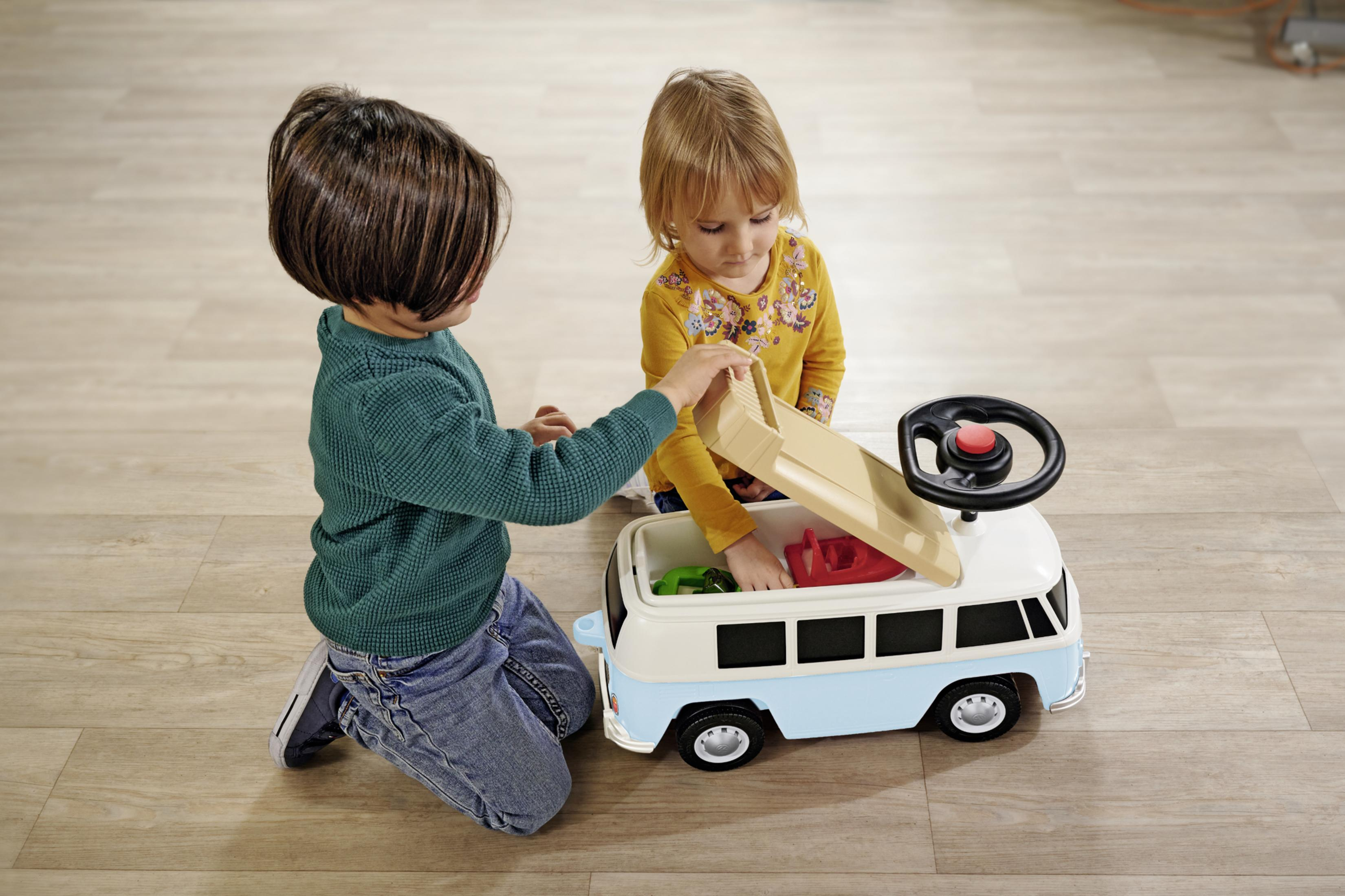 Zwei Kinder spielen mit einem Spielzeugbus, einer öffnet das Dach, der andere schaut zu.