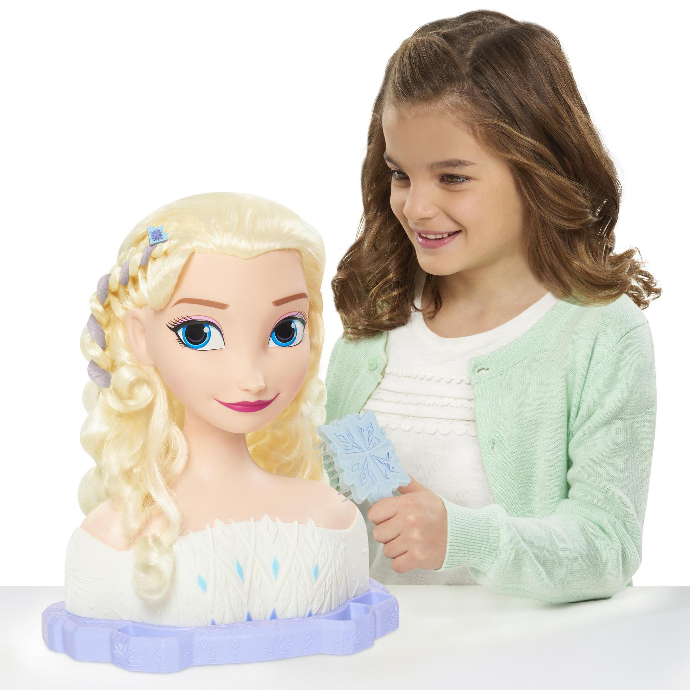Una ragazza acconcia i capelli di una bambola Elsa. La testa di Elsa è su un vassoio.