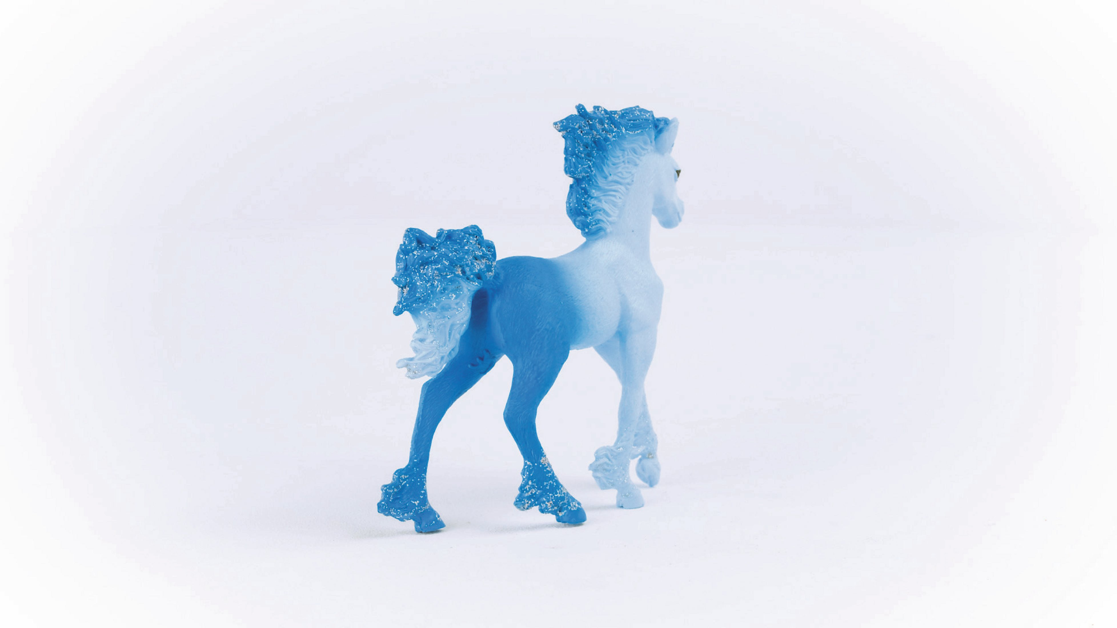 Niebieski zabawkowy koń stoi tyłem do widza na białym tle.
