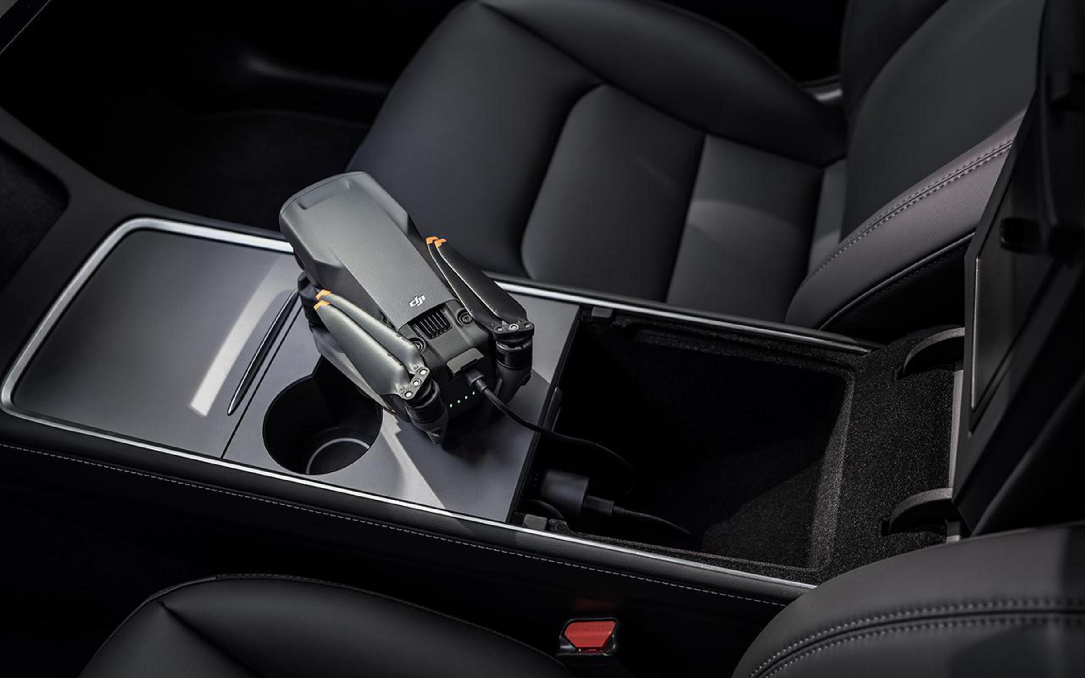 Drone nella console dell'auto, in carica. Drone nero, interni neri, dettagli argento.