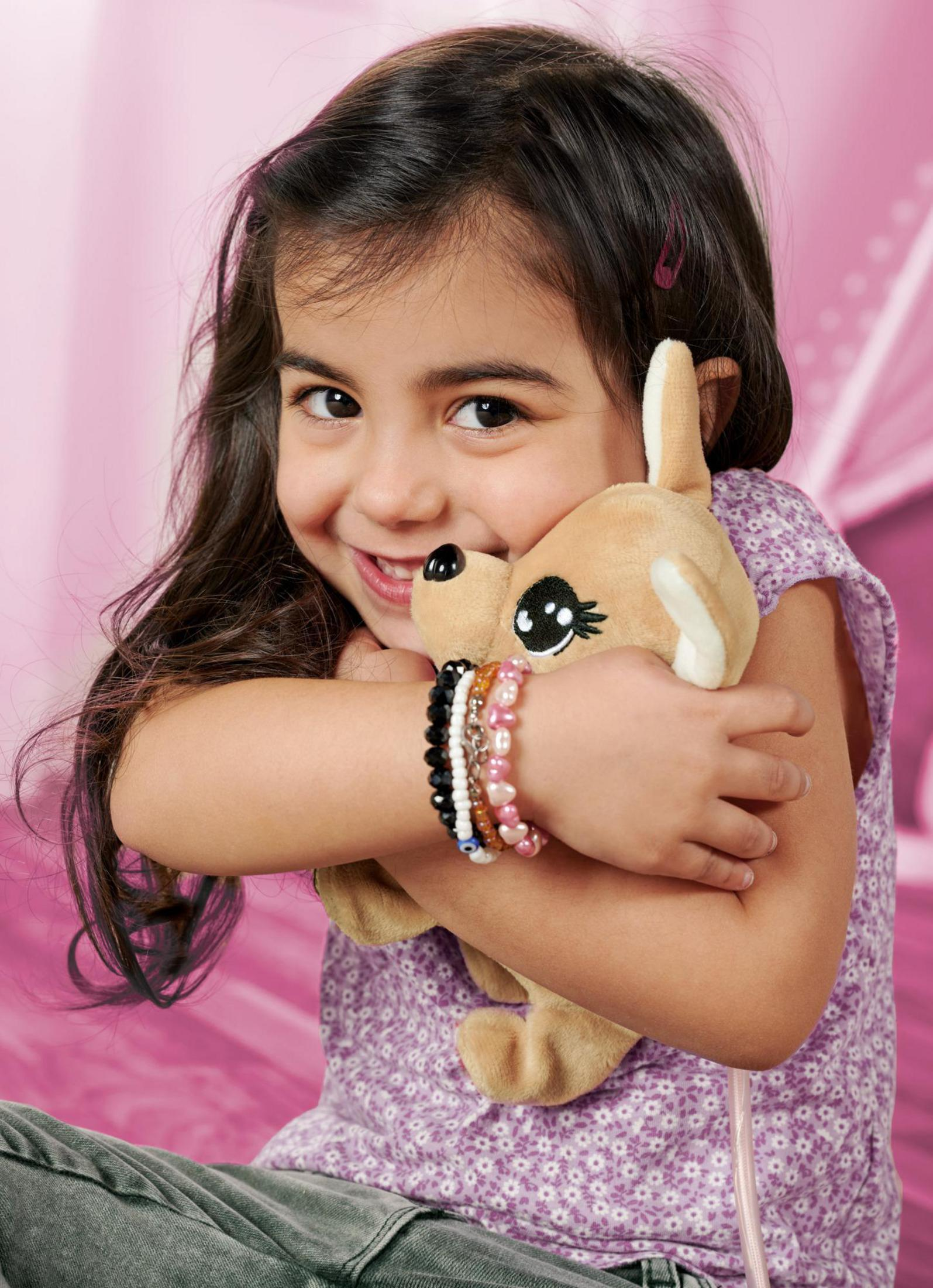 Niña con cabello oscuro abrazando un ciervo de juguete, usando pulseras.