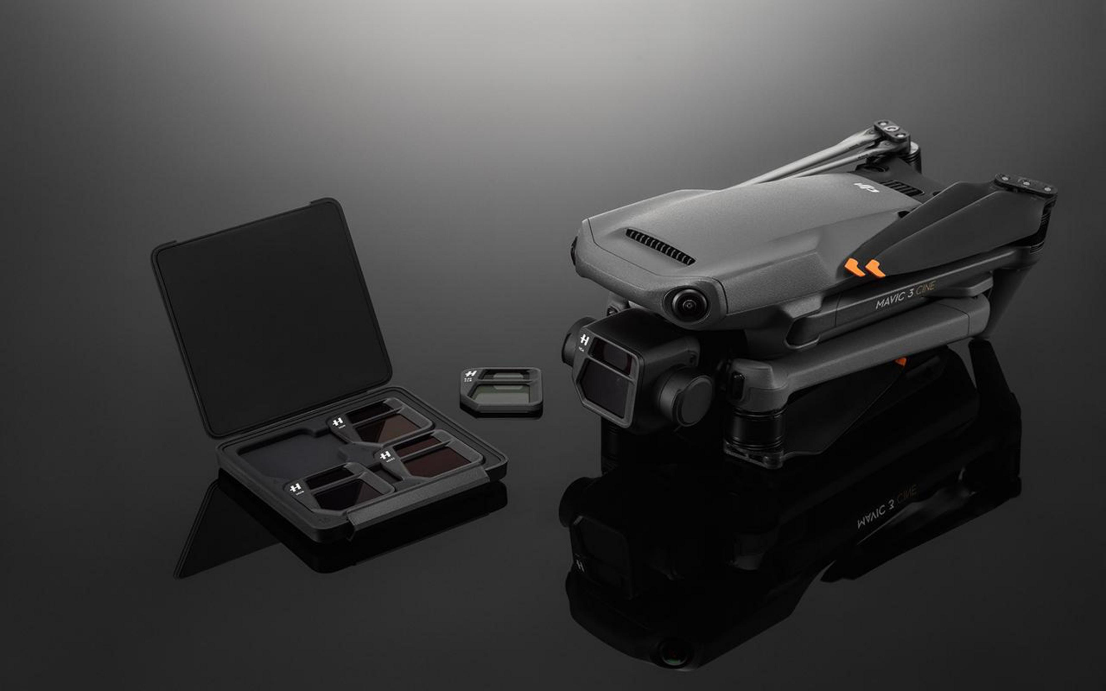 Un drone, filtri per fotocamera e una custodia, il tutto su una superficie nera riflettente.
