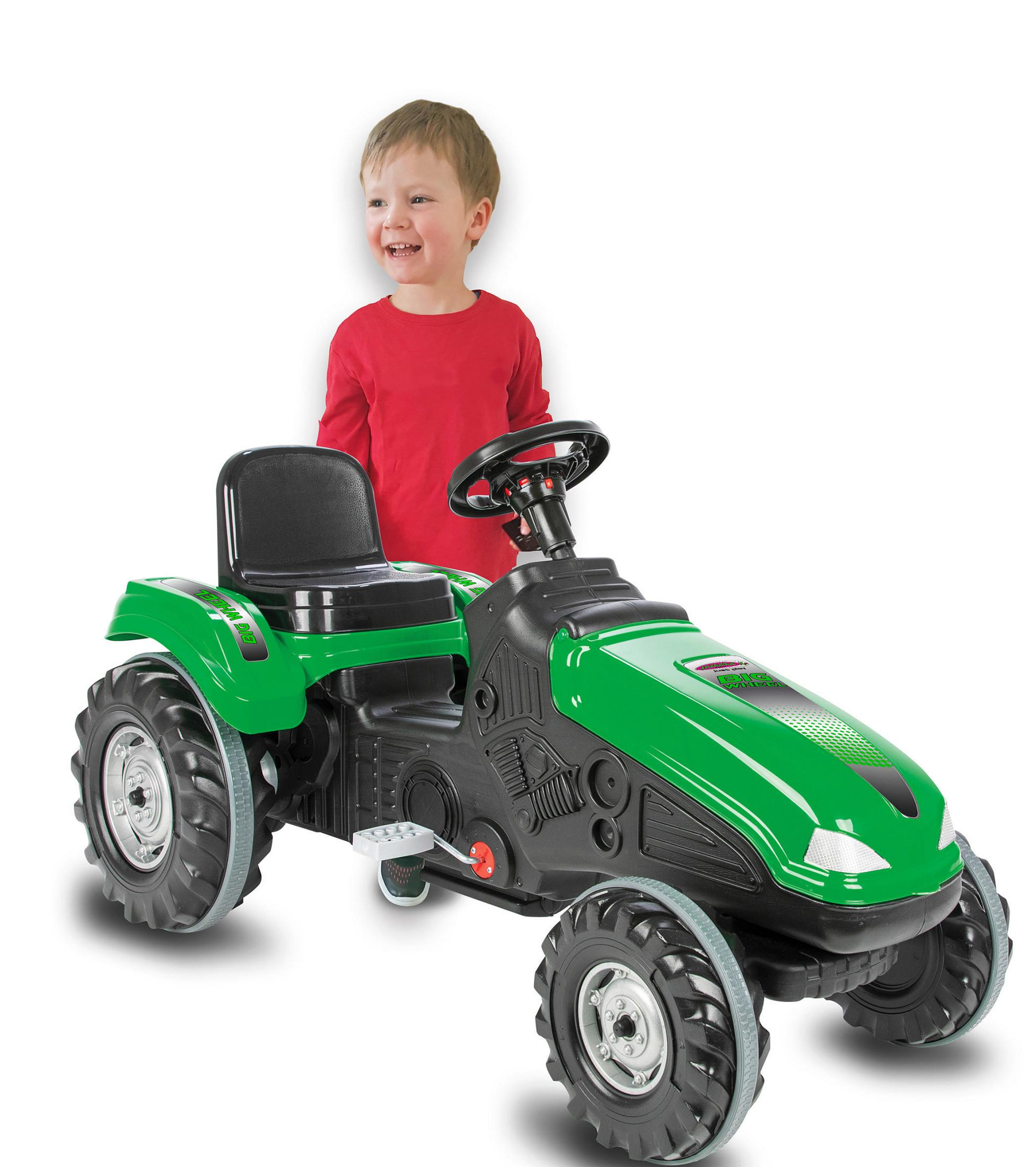Ein lächelnder Junge in Rot steht hinter einem grünen Spielzeugtraktor. Der Traktor hat schwarze Räder und Sitz.