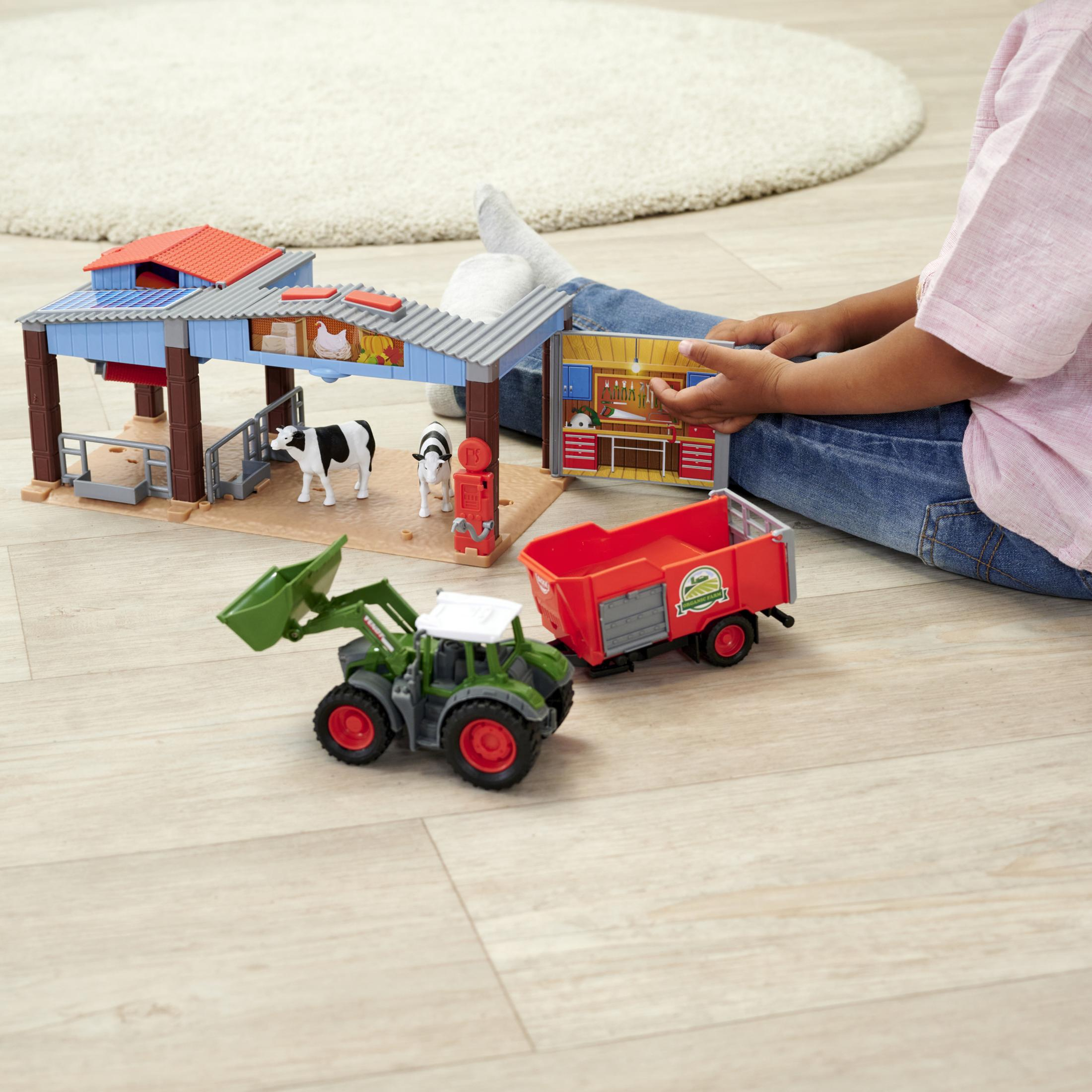 Ein Kind spielt mit einem Spielzeug-Bauernhof-Set auf einem Holzboden. Ein Traktor und Kühe sind vorhanden.