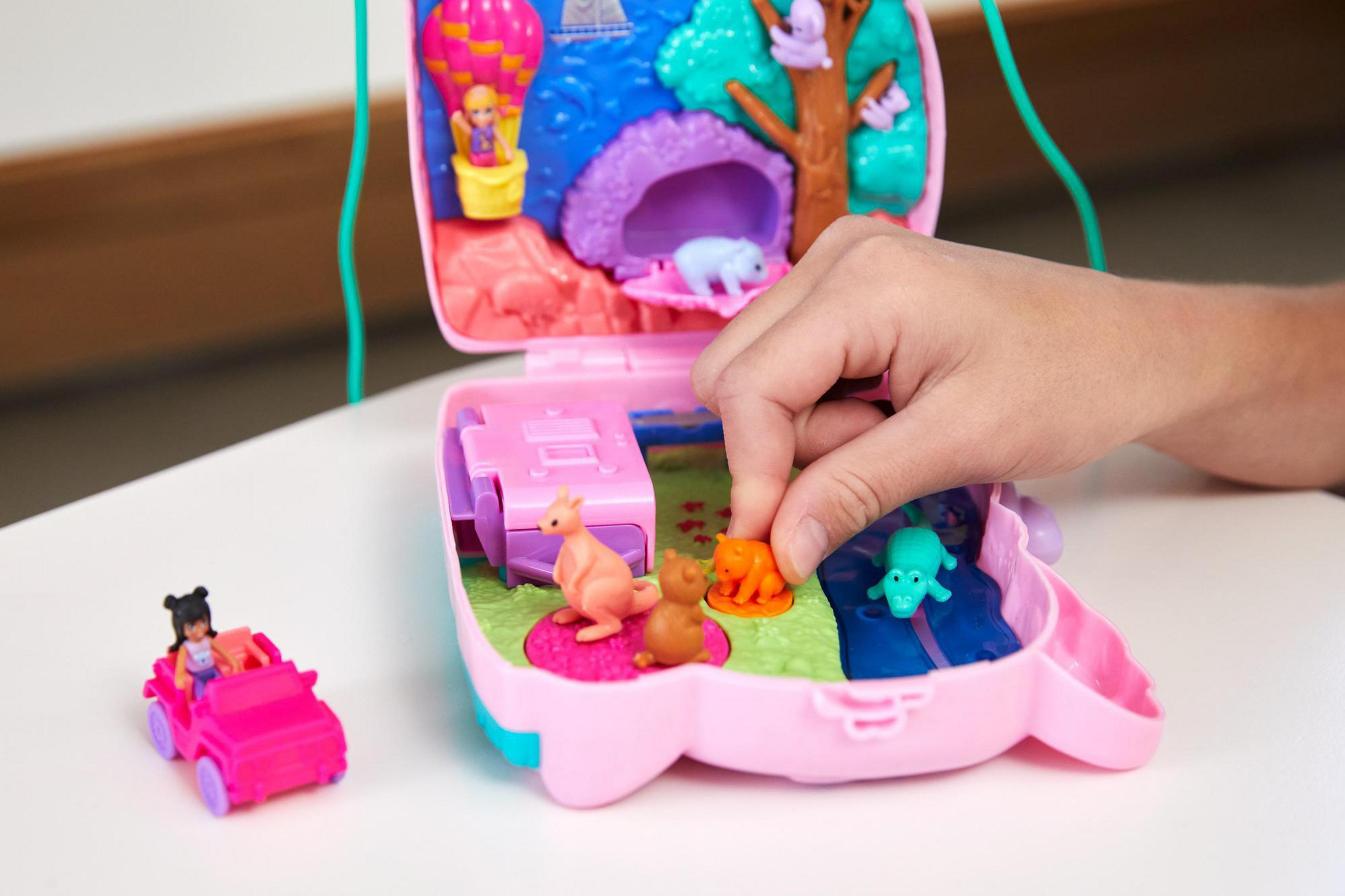 Dziecko bawi się różową zabawką. Ma mały samochód, zwierzęta i krajobraz.