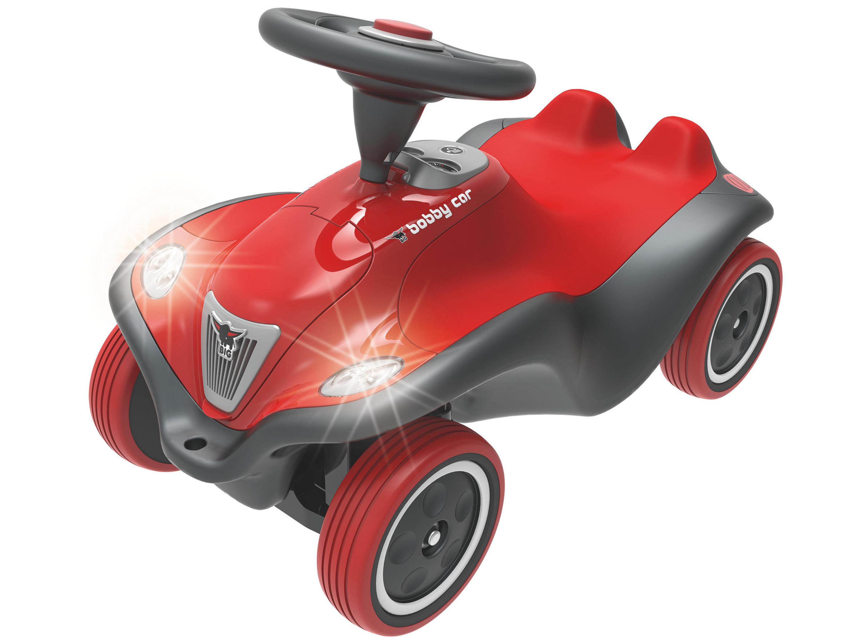 Rotes und graues Kunststoff-Spielzeugauto. Es hat ein Lenkrad, Scheinwerfer und steht auf weißem Untergrund.