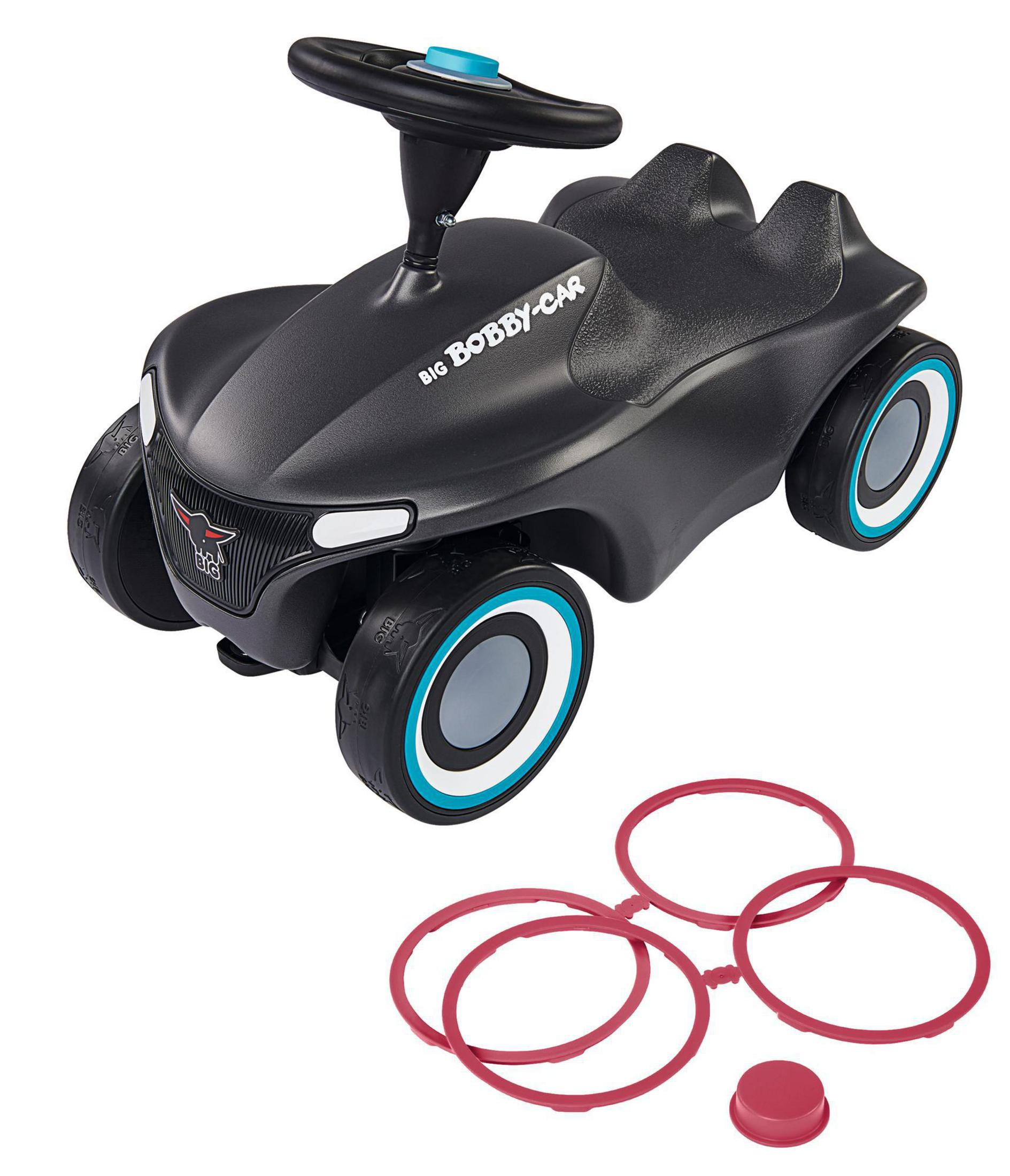 Schwarzes Bobby-Car Spielzeugauto mit roten Zubehörteilen. Weißer Hintergrund.