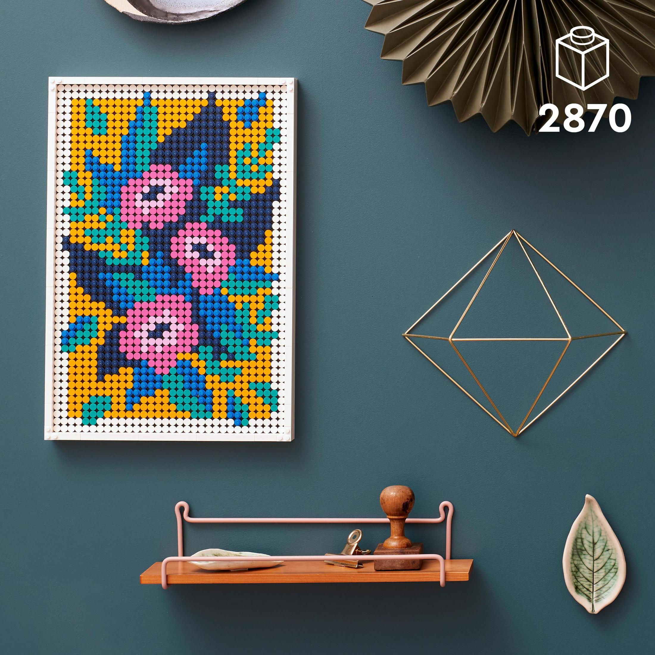 Una obra de arte de mosaico floral en un marco blanco. Tiene colores azul, amarillo y rosa.