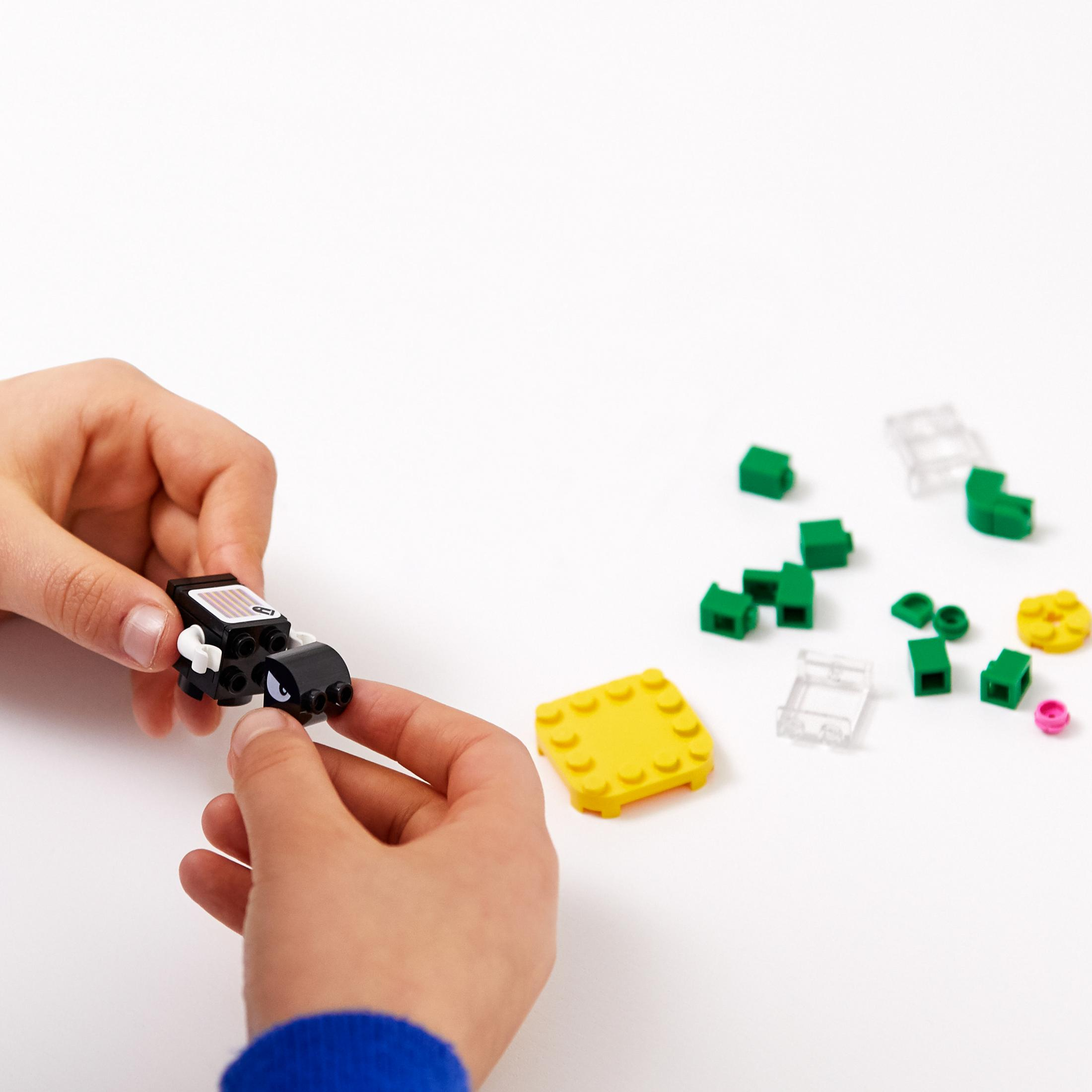 Mani che assemblano mattoncini Lego, vari colori, su sfondo bianco.