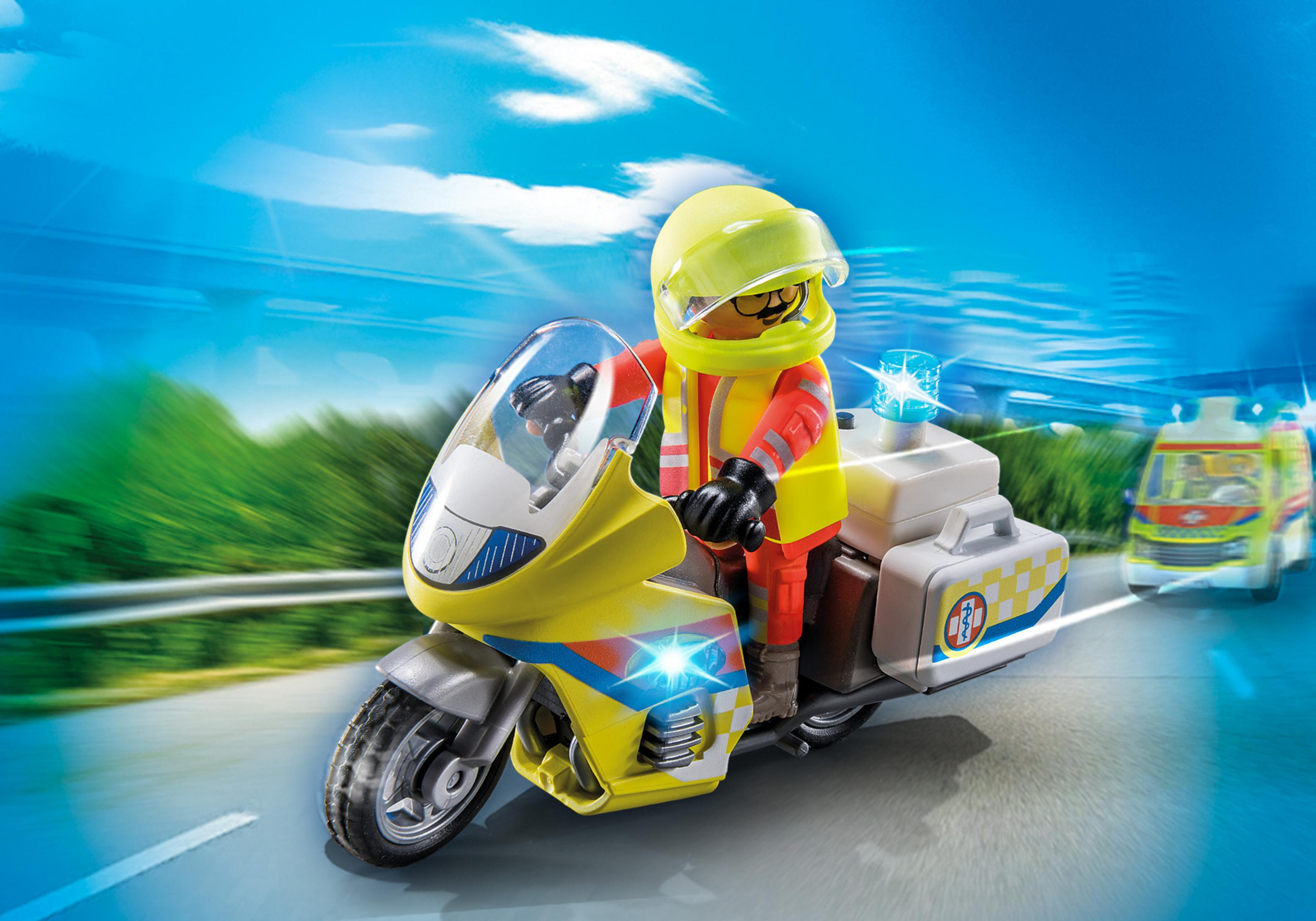 Poliziotto giocattolo su una moto, con un casco giallo, che va verso destra. Un'ambulanza sullo sfondo.