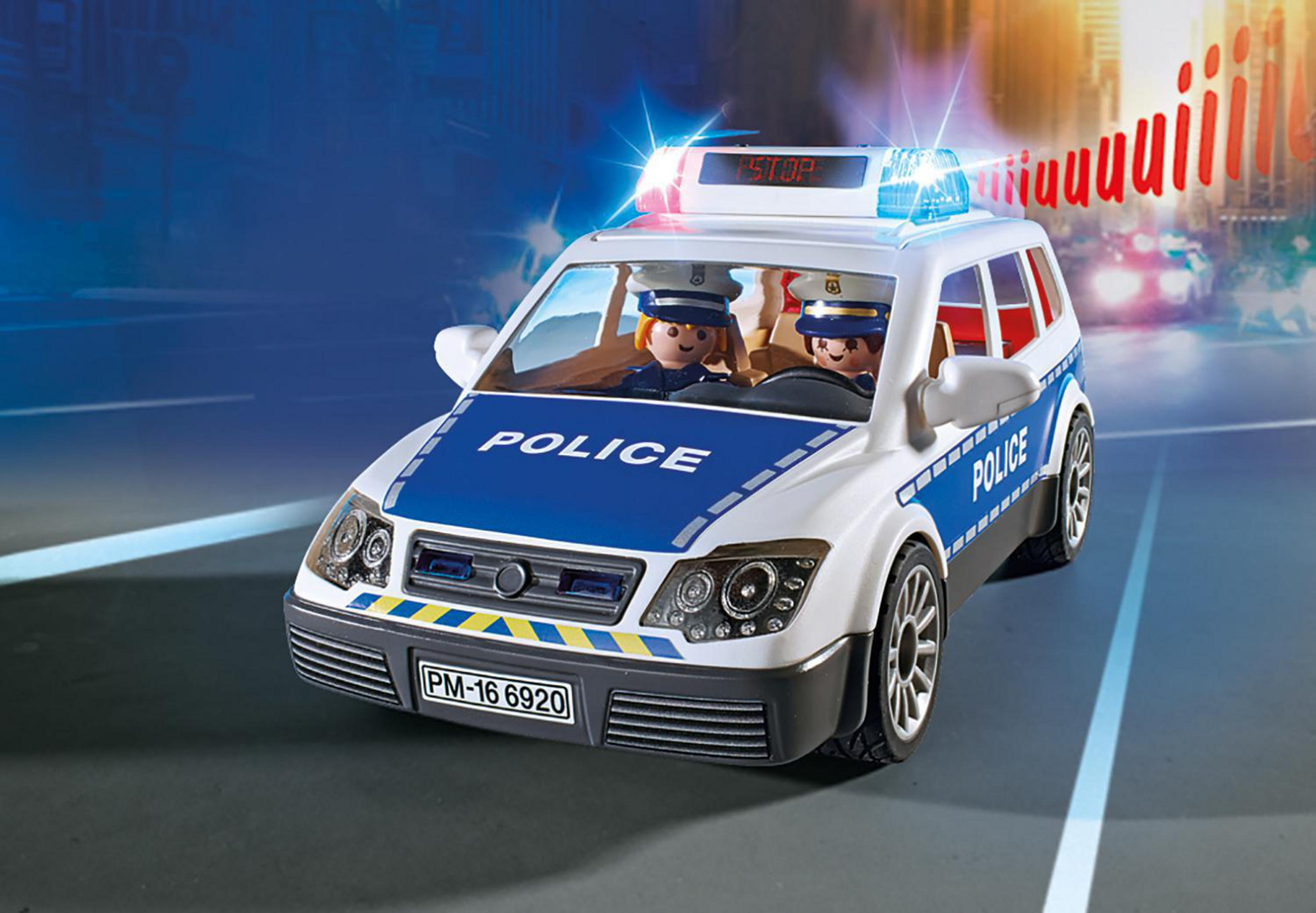 Auto della polizia Playmobil con due personaggi all'interno. Luci brillanti e sfondo sfocato.