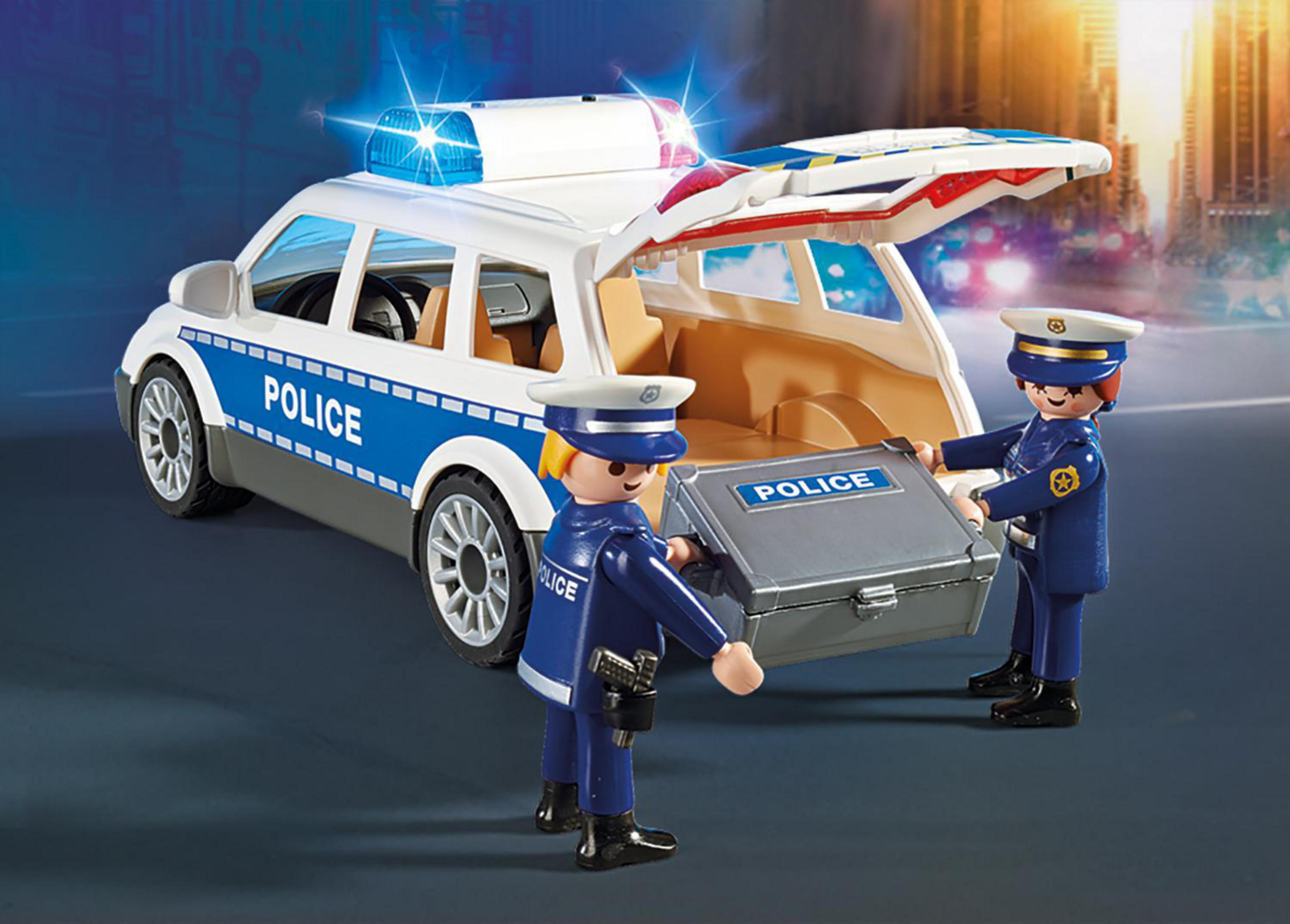 Auto della polizia giocattolo con agenti che caricano una valigia, sfondo urbano.