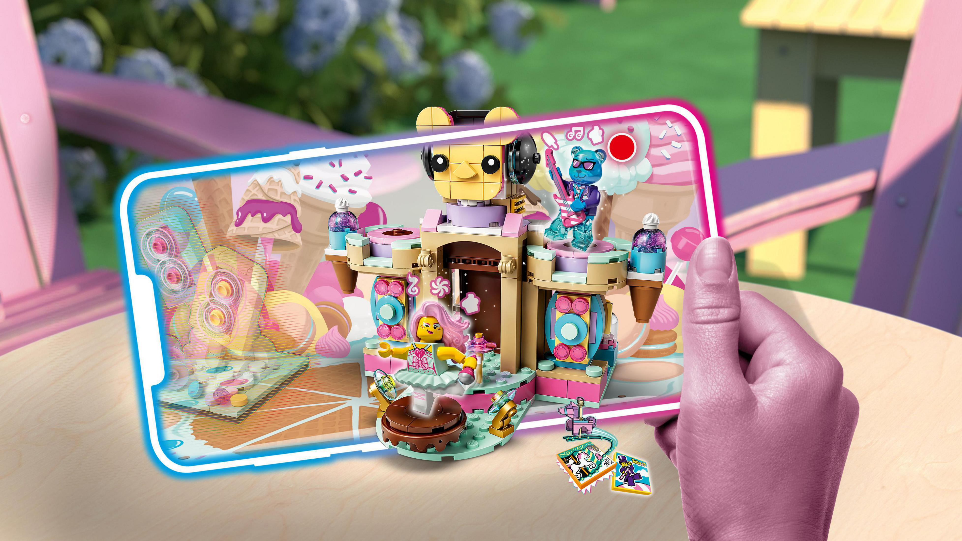 Model Lego na ekranie telefonu. Scena, miś DJ, tancerze i słodycze.