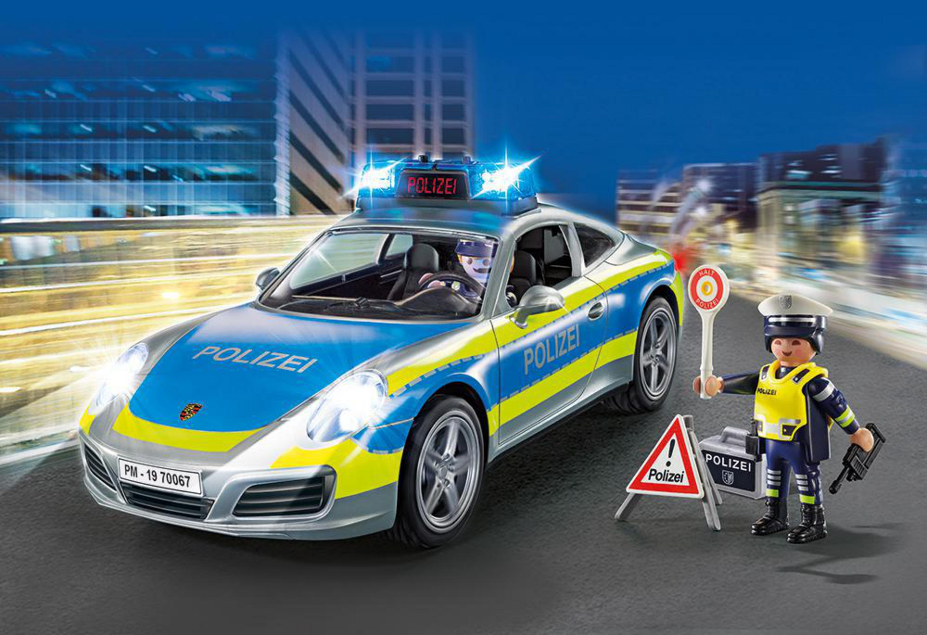 Ein Spielzeug-Polizeiauto mit eingeschaltetem Licht, ein Polizist und Verkehrsschilder. Die Szene spielt nachts, mit Stadtlichtern.