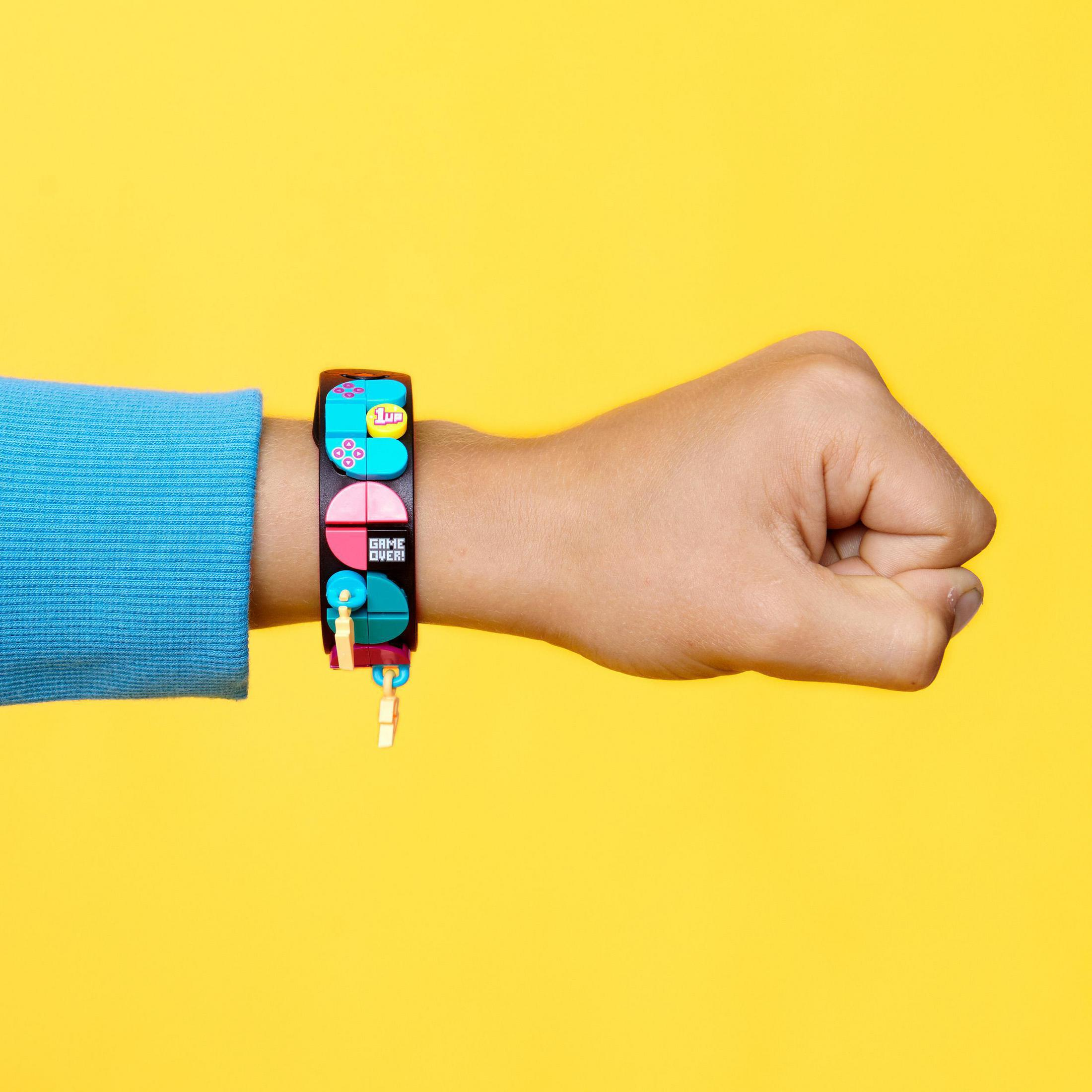 Kinderhand mit einem bunten Armband mit Spielcontroller- und Game-Over-Symbolen.