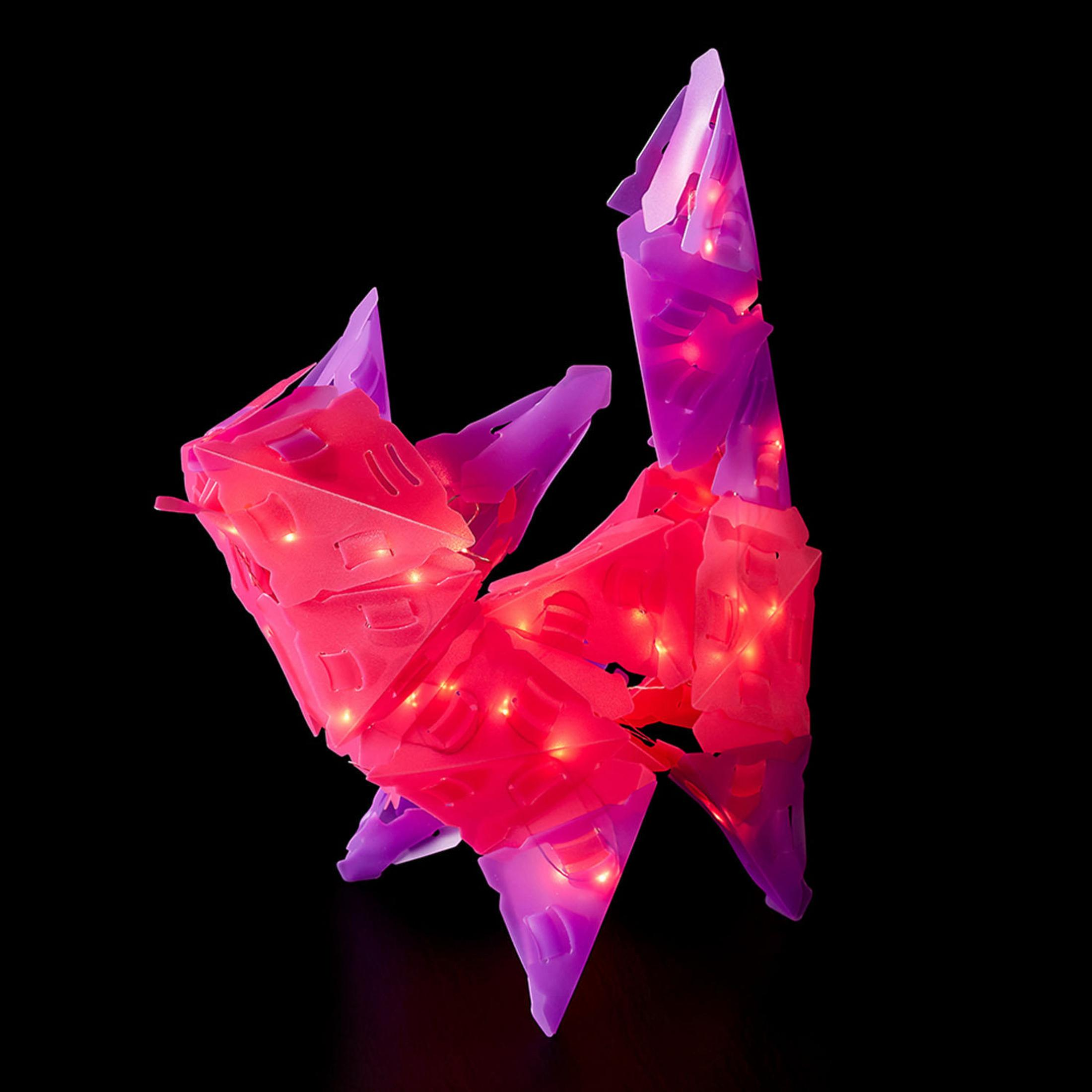 Abstrakte Skulptur mit bunten LED-Leuchten vor dunklem Hintergrund. Die Farben sind rosa und lila.