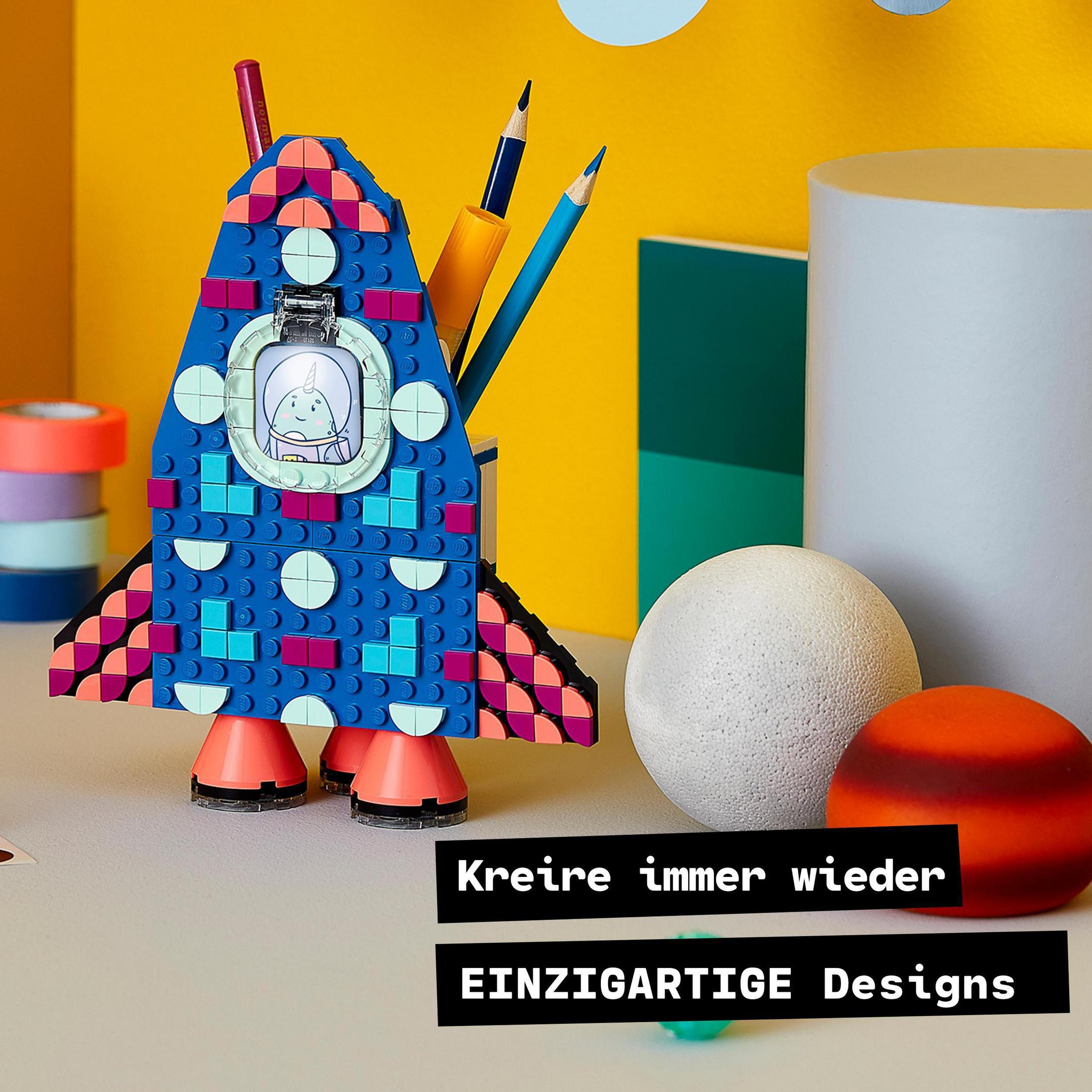 Eine Lego-Rakete mit bunten Details und Text: „EINZIGARTIGE Designs“. Stifte und Kugeln in der Nähe.