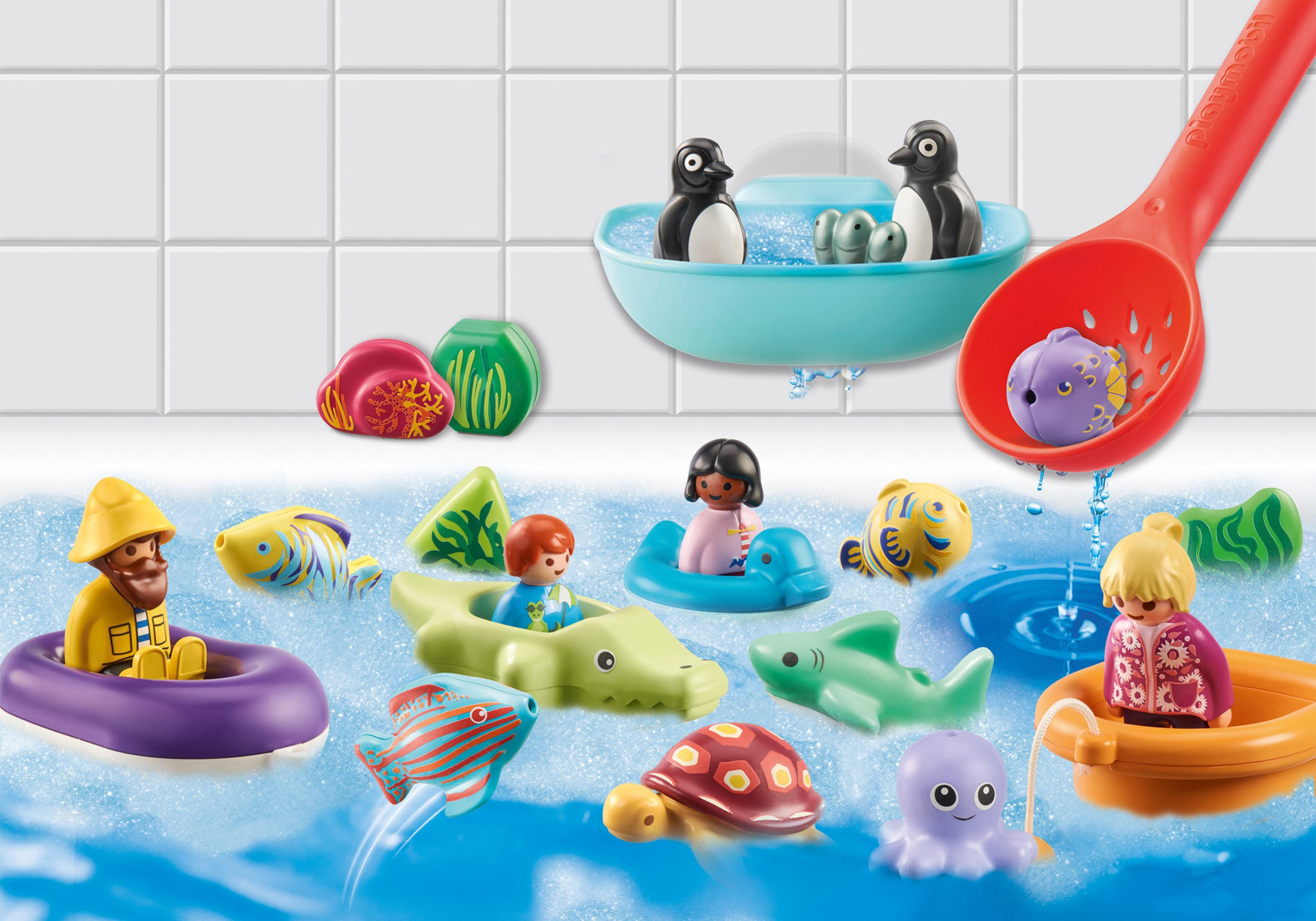 Giocattoli in un bagno. Pinguini in una vasca, personaggi in barca, pesci e una paletta rossa con acqua che versa.