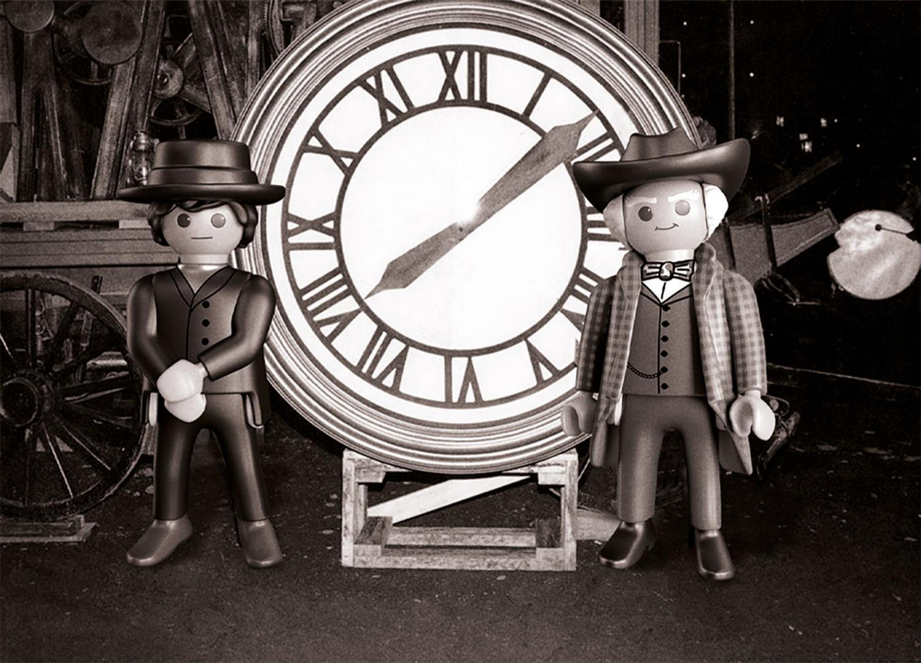 Spielfiguren von Männern mit Hüten, die vor einer Uhr stehen, Schwarz-Weiß-Foto.