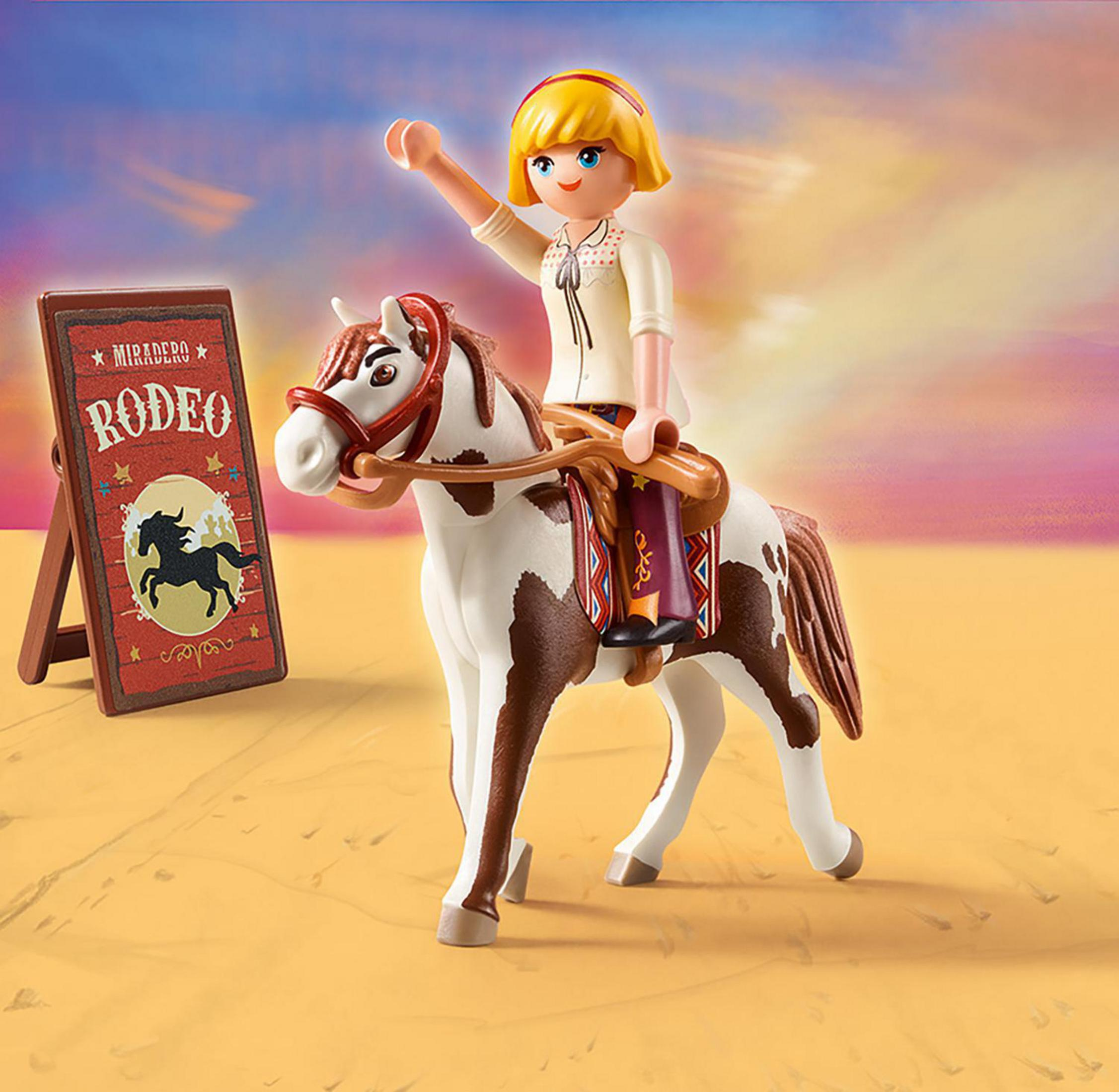 Spielzeug-Cowgirl reitet auf einem weiß-braunen Pferd. Ein Schild sagt 'Rodeo'.