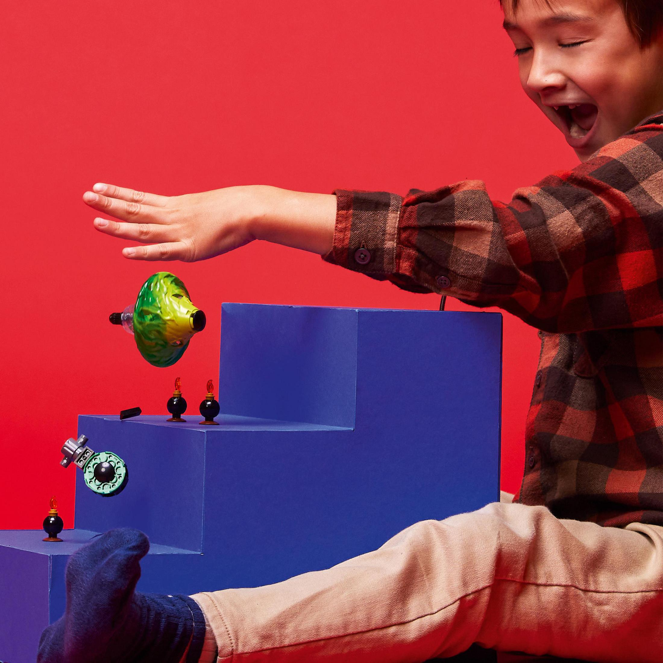 Un enfant jouant avec des jouets. Marches bleues, jouet vert et jaune sur fond rouge.