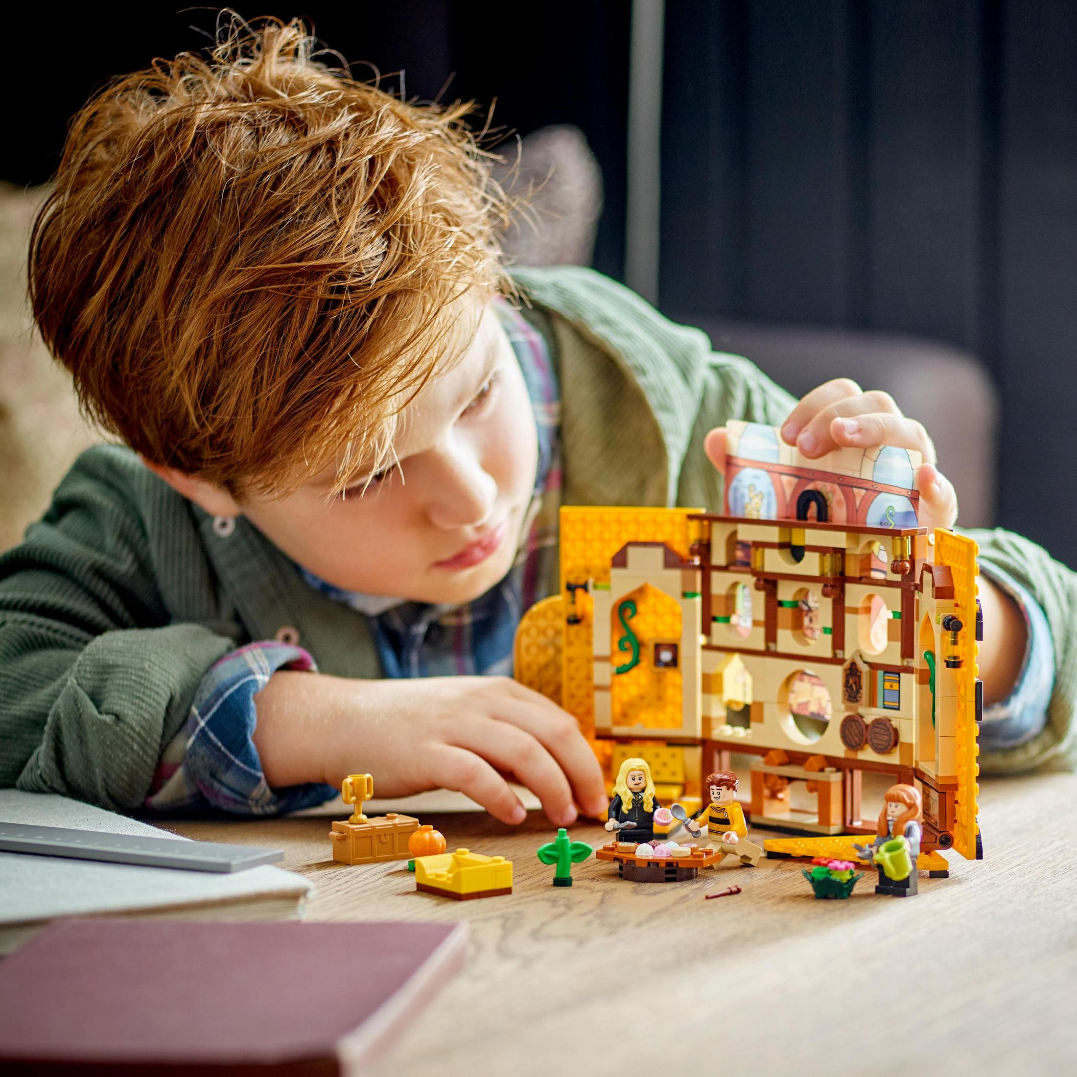 Junge spielt mit LEGO Harry Potter Set, baut eine Szene mit Figuren und Requisiten.