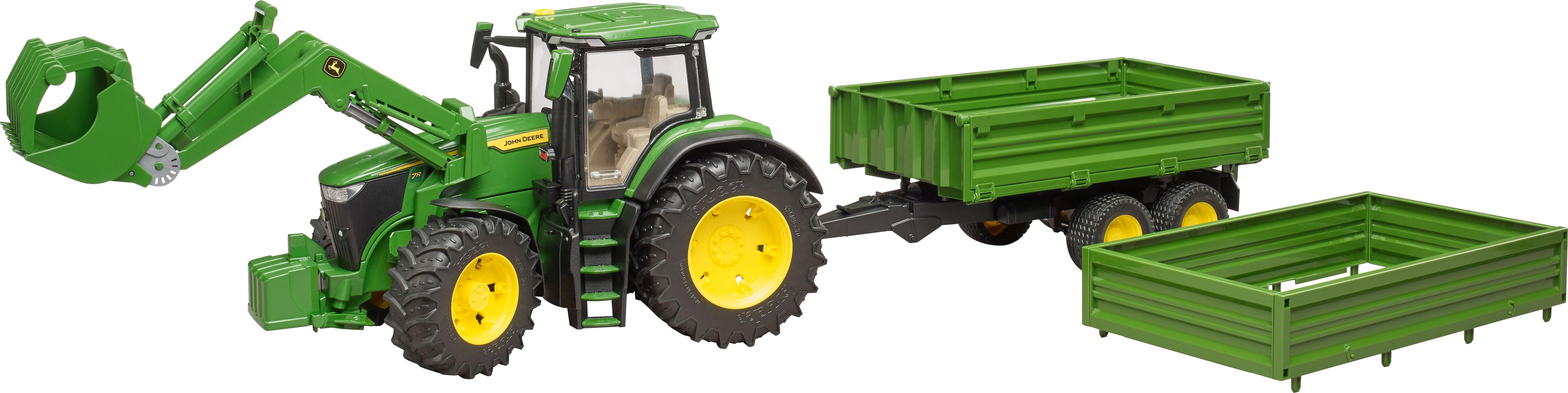 Ein grüner Traktor mit Anhänger und einem zusätzlichen Container. Der Traktor hat einen Frontlader.