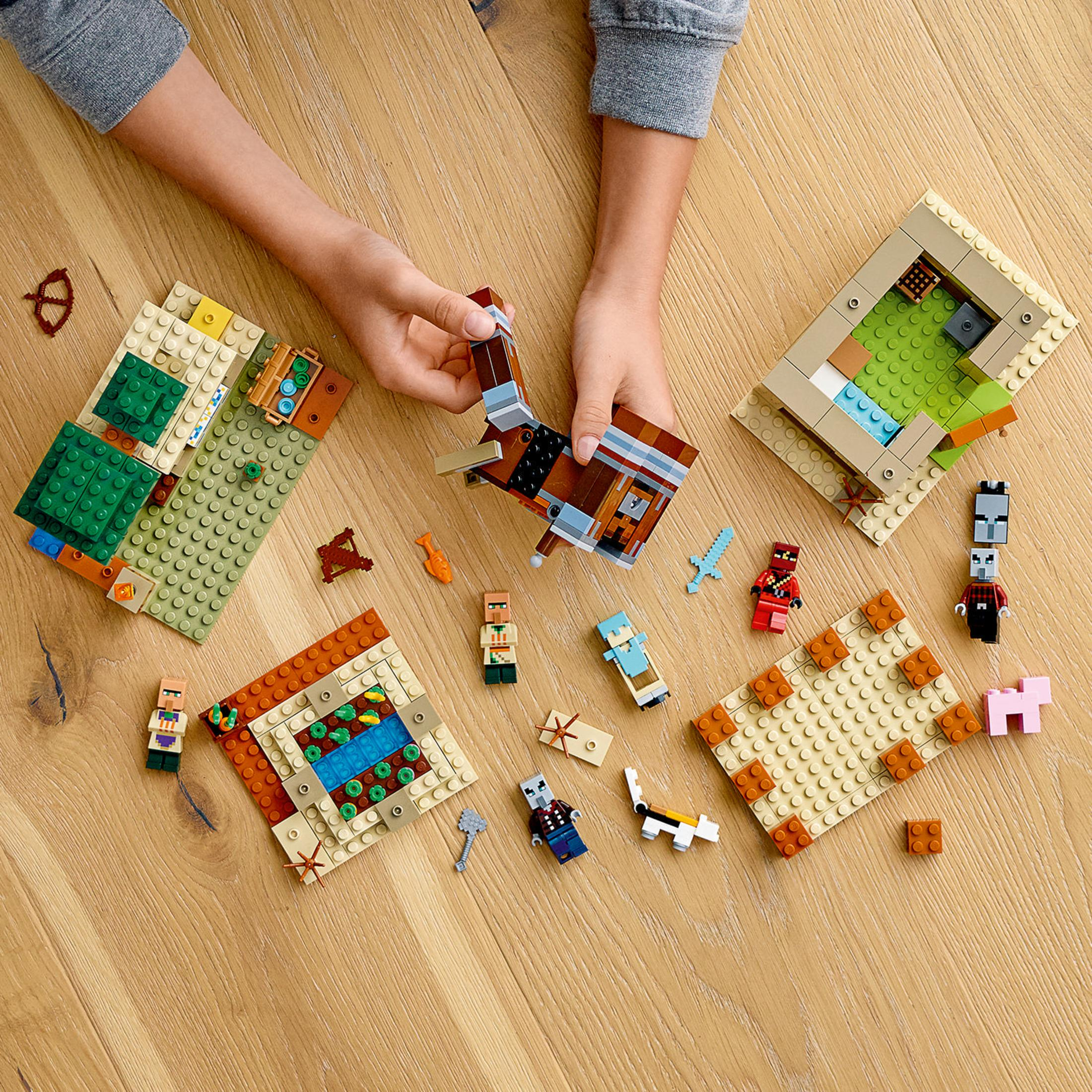 Un set Lego di Minecraft con più costruzioni e figure su una superficie di legno, creando una scena di villaggio.