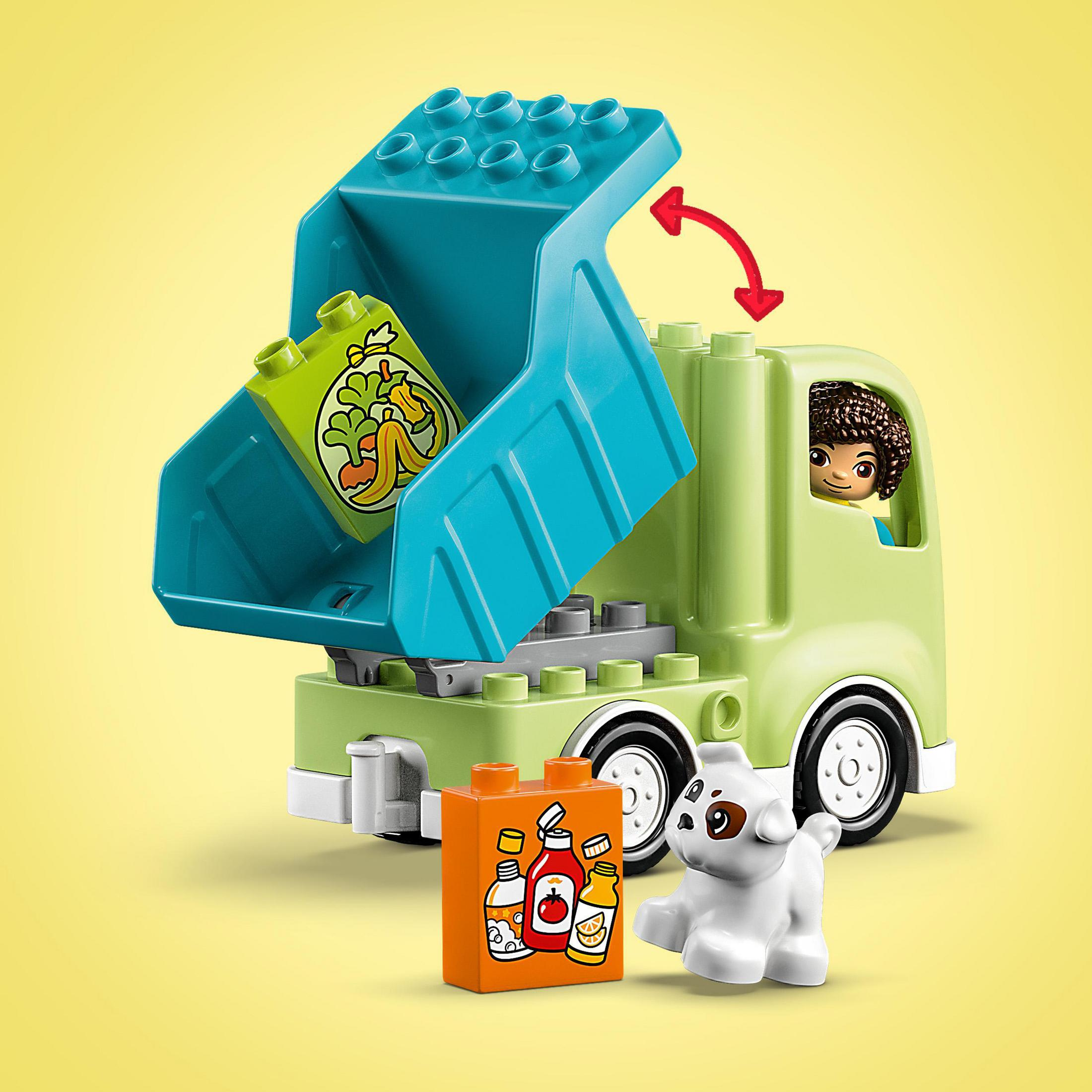 Ein grüner Spielzeug-LKW mit einer Kinderfigur in der Kabine, einer Lebensmittelkiste und einem Spielzeughund.