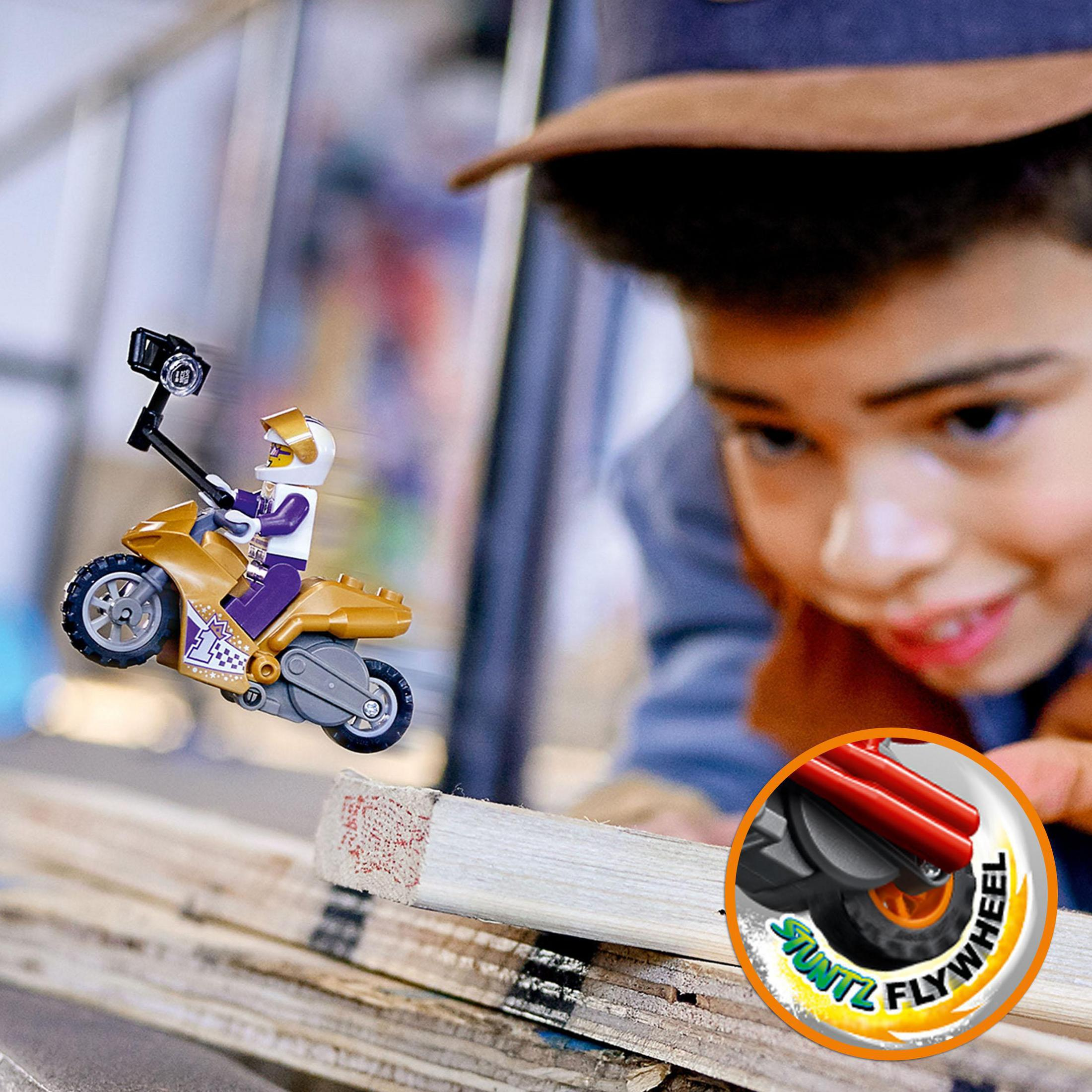 Bir çocuk, tahta tahtalar üzerinde, bir Lego dublör motosikletini izliyor.