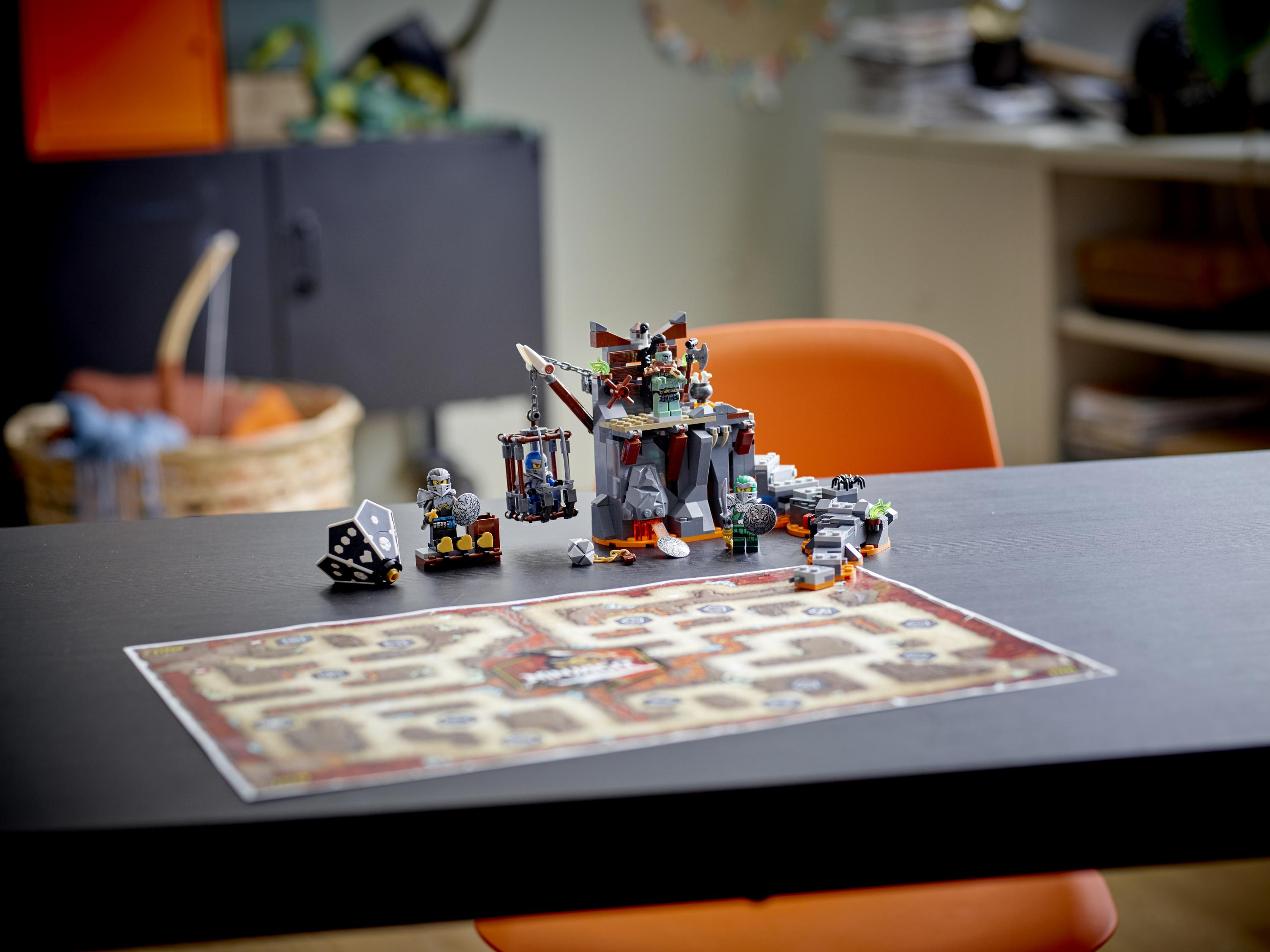 Ein Lego-Spielset auf einem Tisch mit einem Spielbrett, einer Festungsstruktur und Minifiguren in einem Raum.