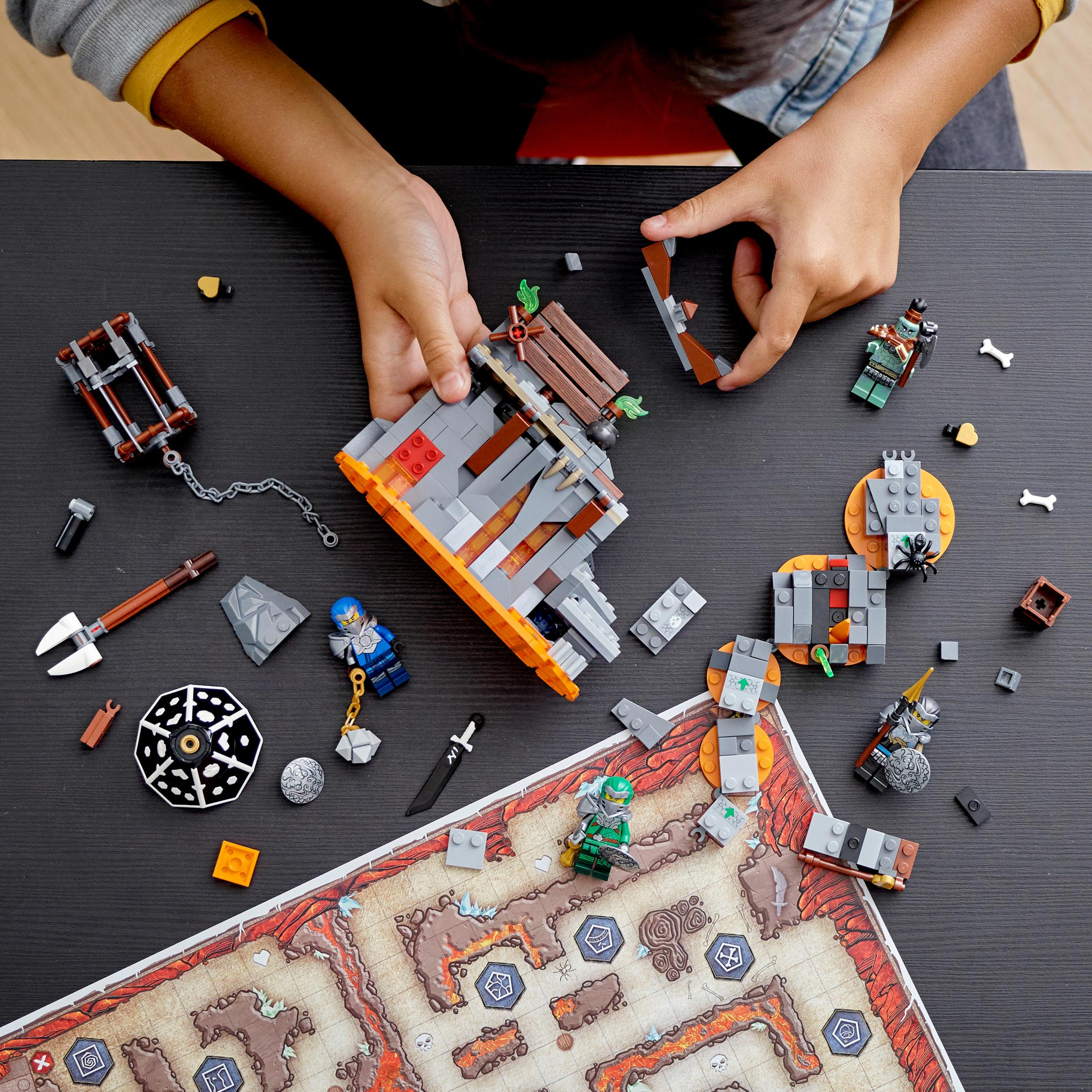 Hände bauen ein Lego-Set mit Brettspiel-Thema, mit Figuren und einer Karte.