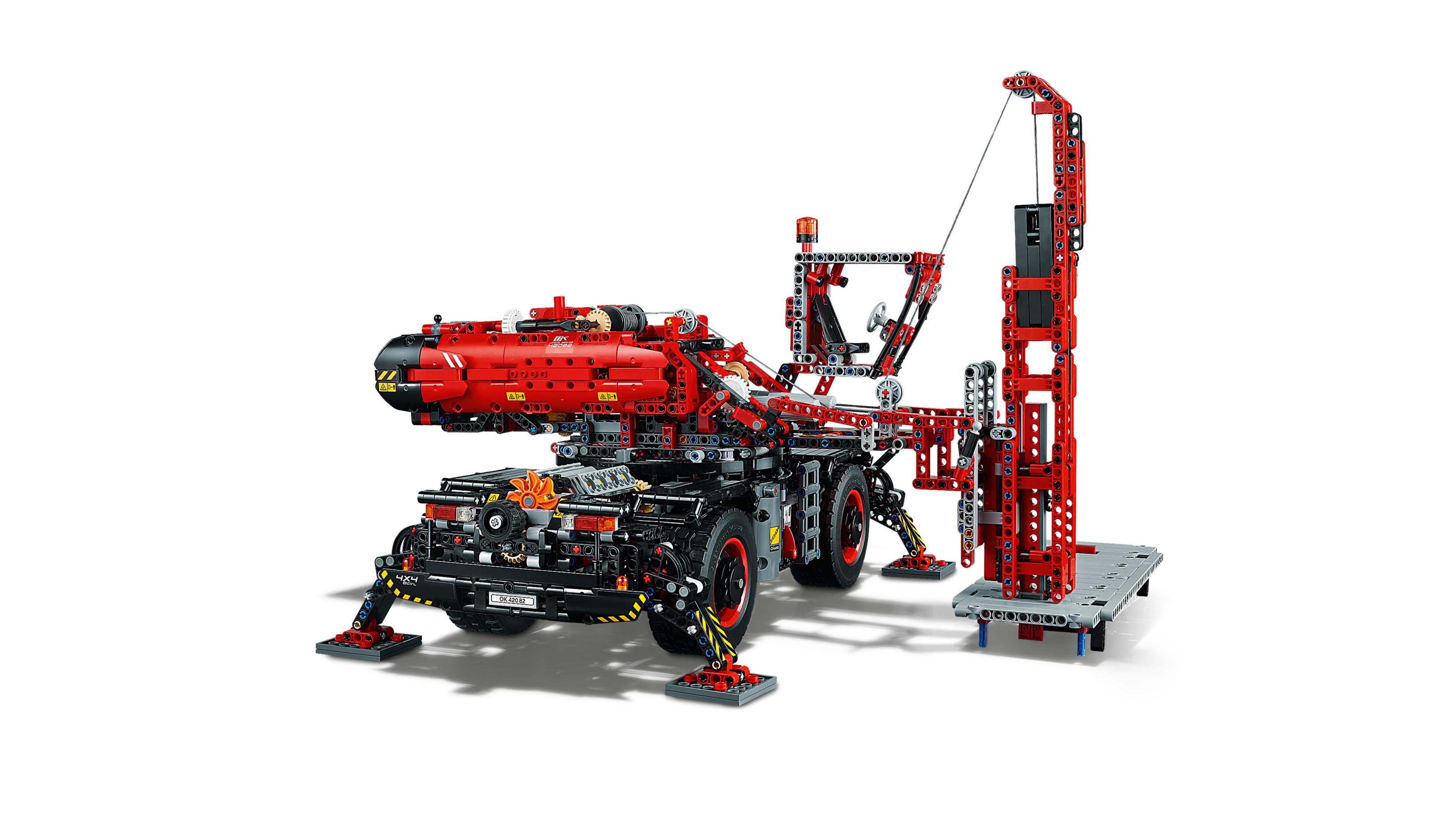 Czerwono-czarny model żurawia LEGO Technic na białym tle, z wieloma ruchomymi częściami i ramieniem dźwigu.