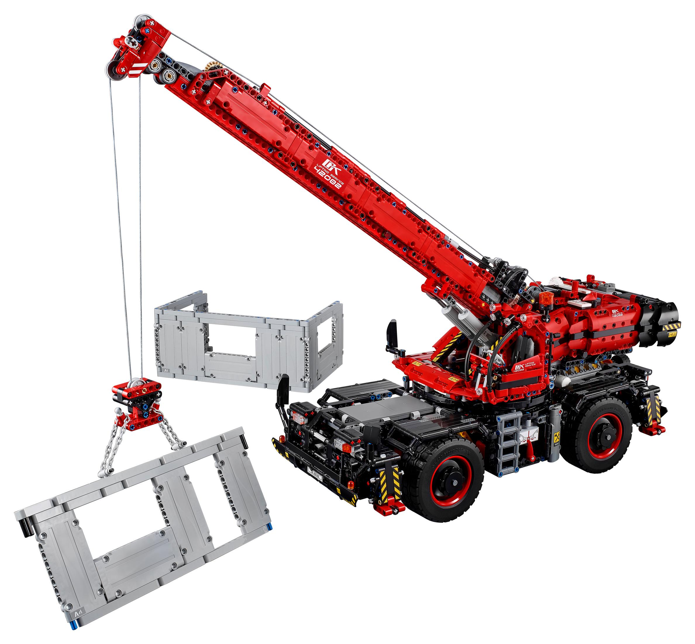 Czerwony i czarny model żurawia Lego Technic, z mechanizmem podnoszenia i oddzielnym budynkiem.