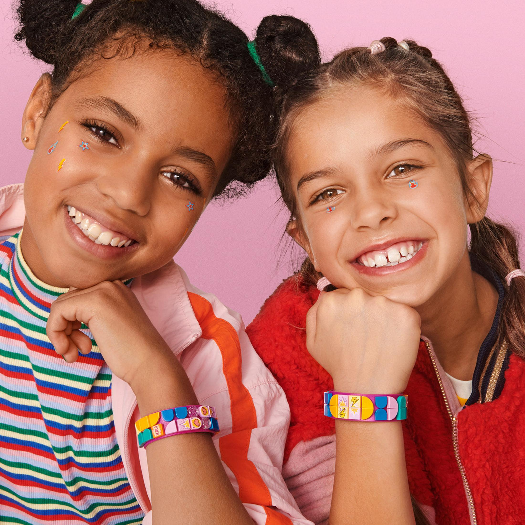 Zwei lächelnde Mädchen mit bunten Armbändern, Aufkleber auf Gesichtern. Nahaufnahme.
