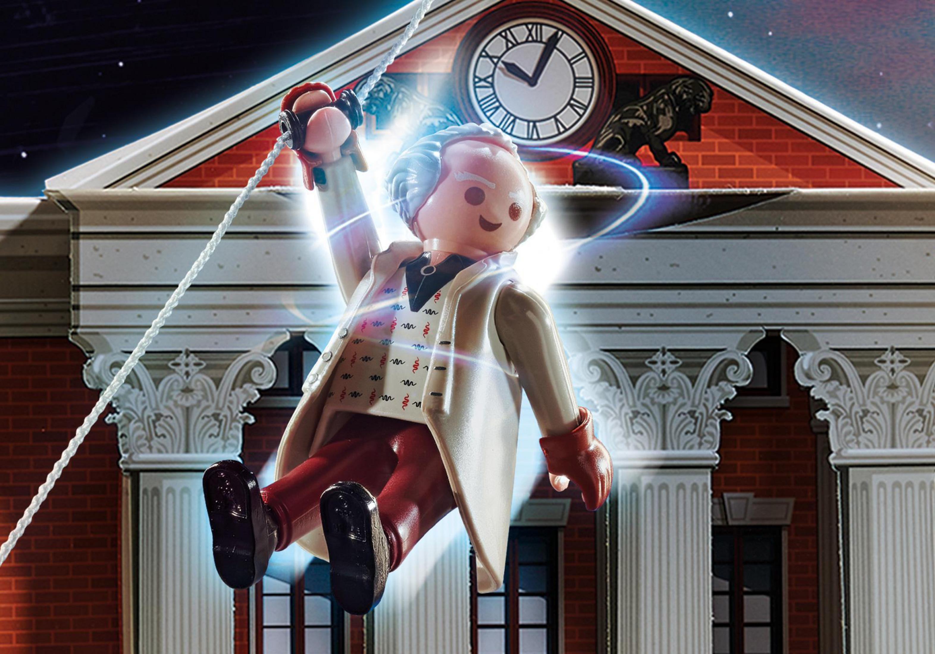 Eine Playmobil-Figur hängt an einem Seil vor einem Gebäude mit Uhr.