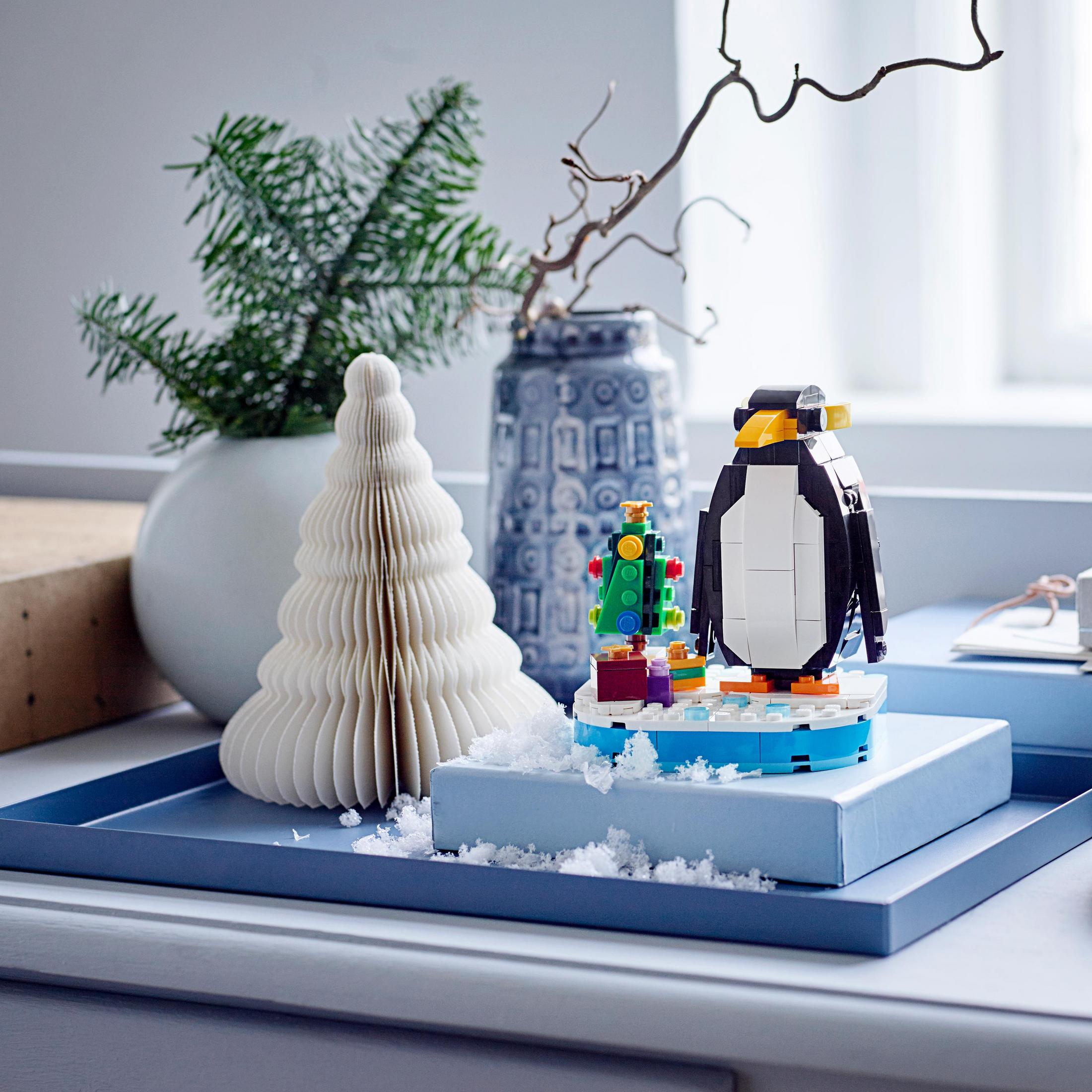 Lego Weihnachtsdisplay: Pinguin auf blauer Basis, Weihnachtsbaum und dekorative Elemente. Hintergrund: weiß.