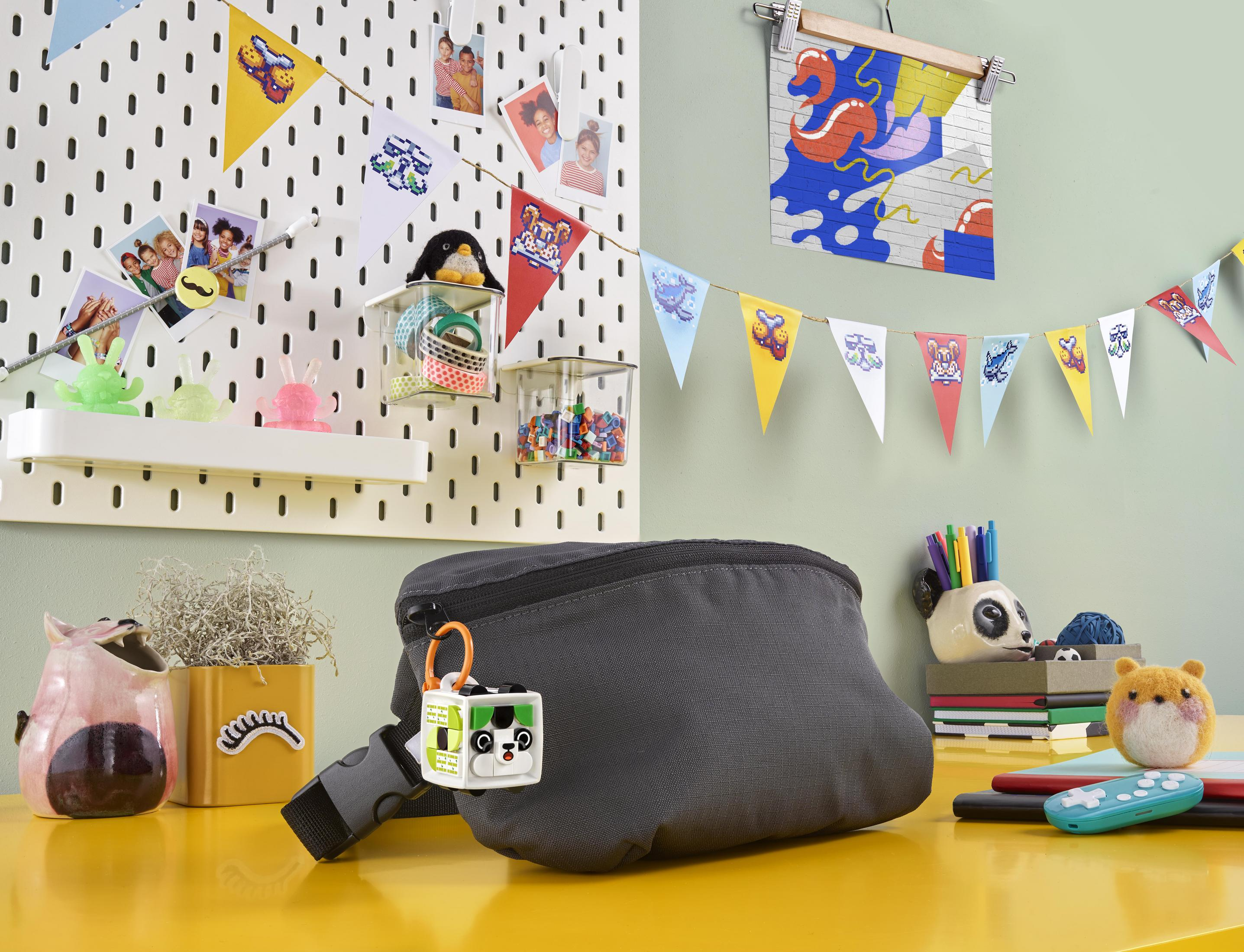 Eine Schreibtischszene mit Bauchtasche, Dekorationen und Schreibwaren auf einer gelben Oberfläche.