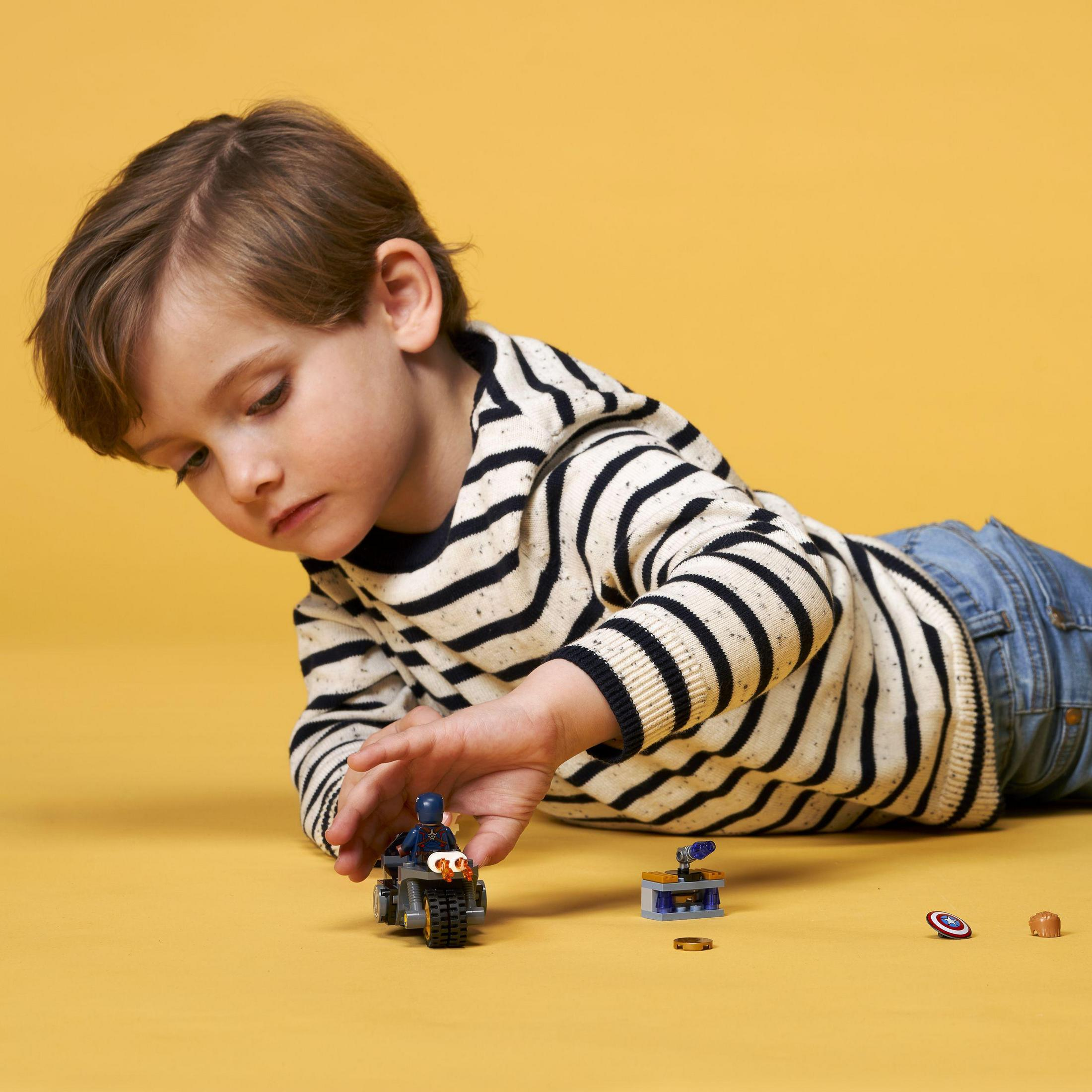 Ein kleiner Junge spielt mit Lego, darunter ein Motorrad und andere kleine Teile.