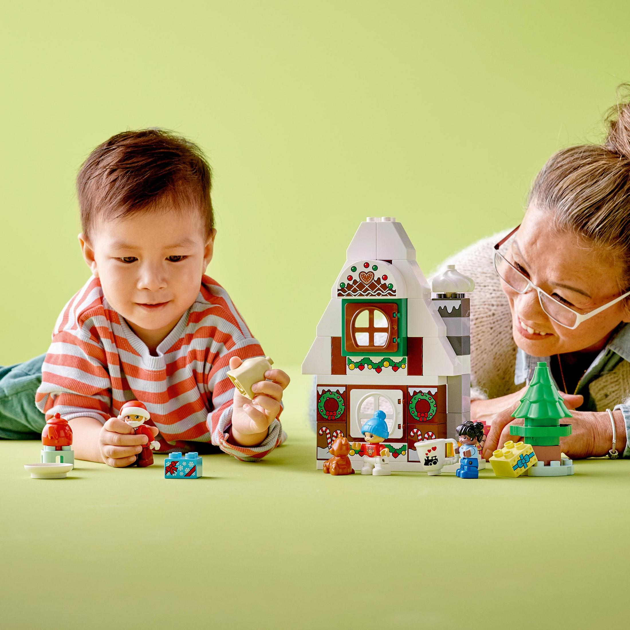 Un niño y una mujer jugando con un set Lego Duplo de casa de jengibre.