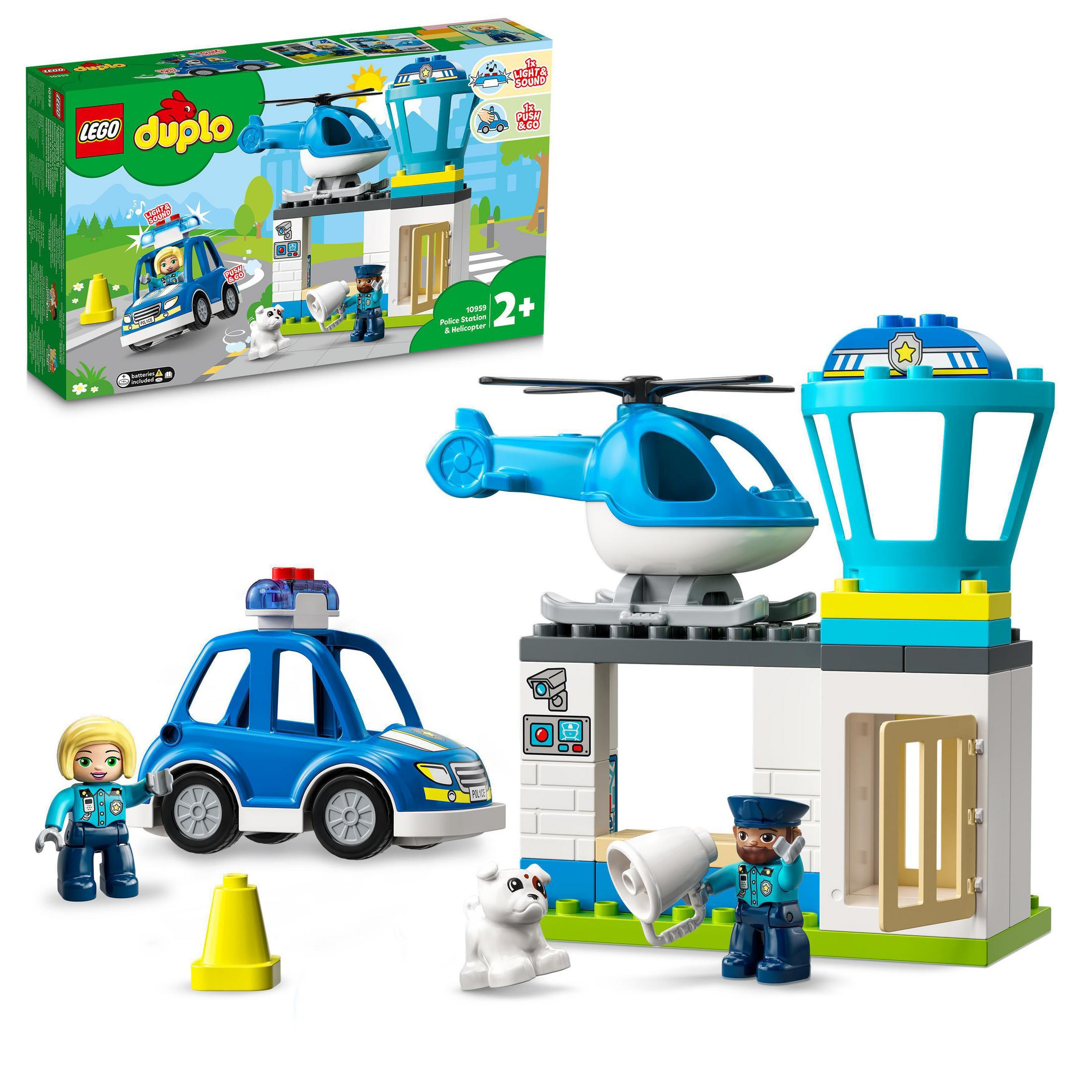 Set de policía Lego Duplo. Muestra una estación de policía, un coche, un helicóptero, figuras y un perro, con una caja.