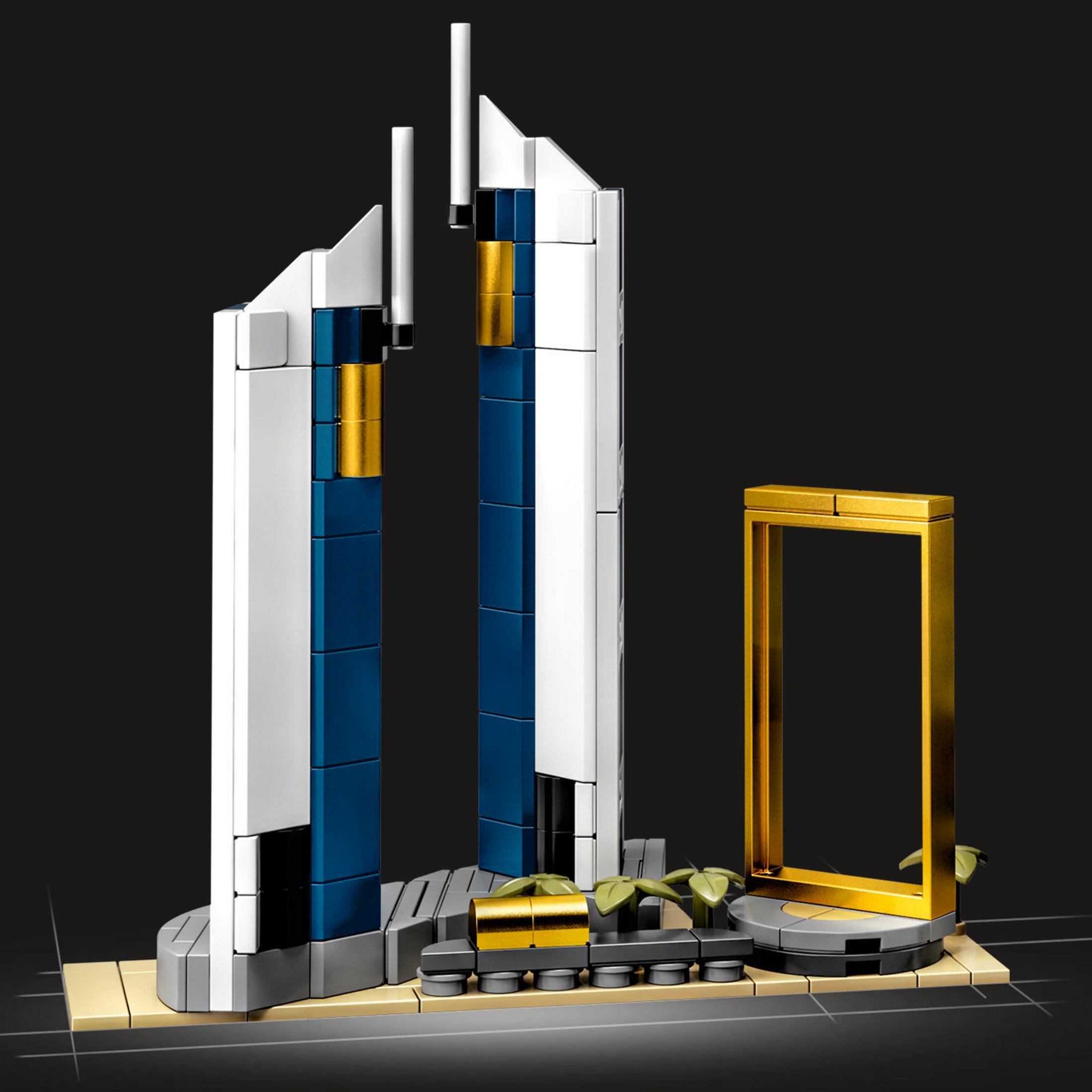 Lego-Set eines modernen Gebäudes mit goldenen Akzenten. Ein goldener Rahmen steht in der Nähe.