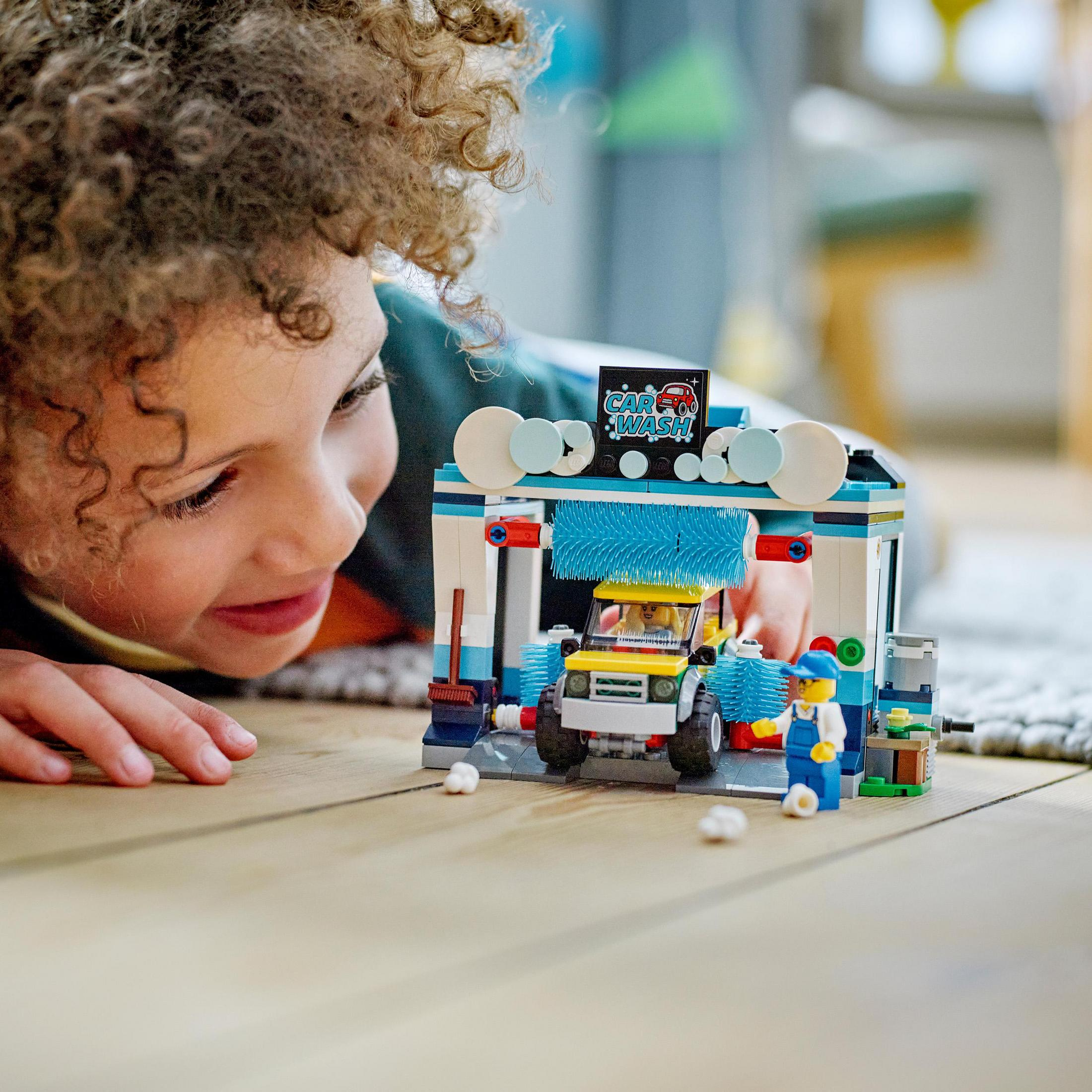 Ein Kind spielt mit einem Lego-Waschanlagen-Set. Das Set beinhaltet ein Auto, Figuren und eine Waschanlagenstruktur.