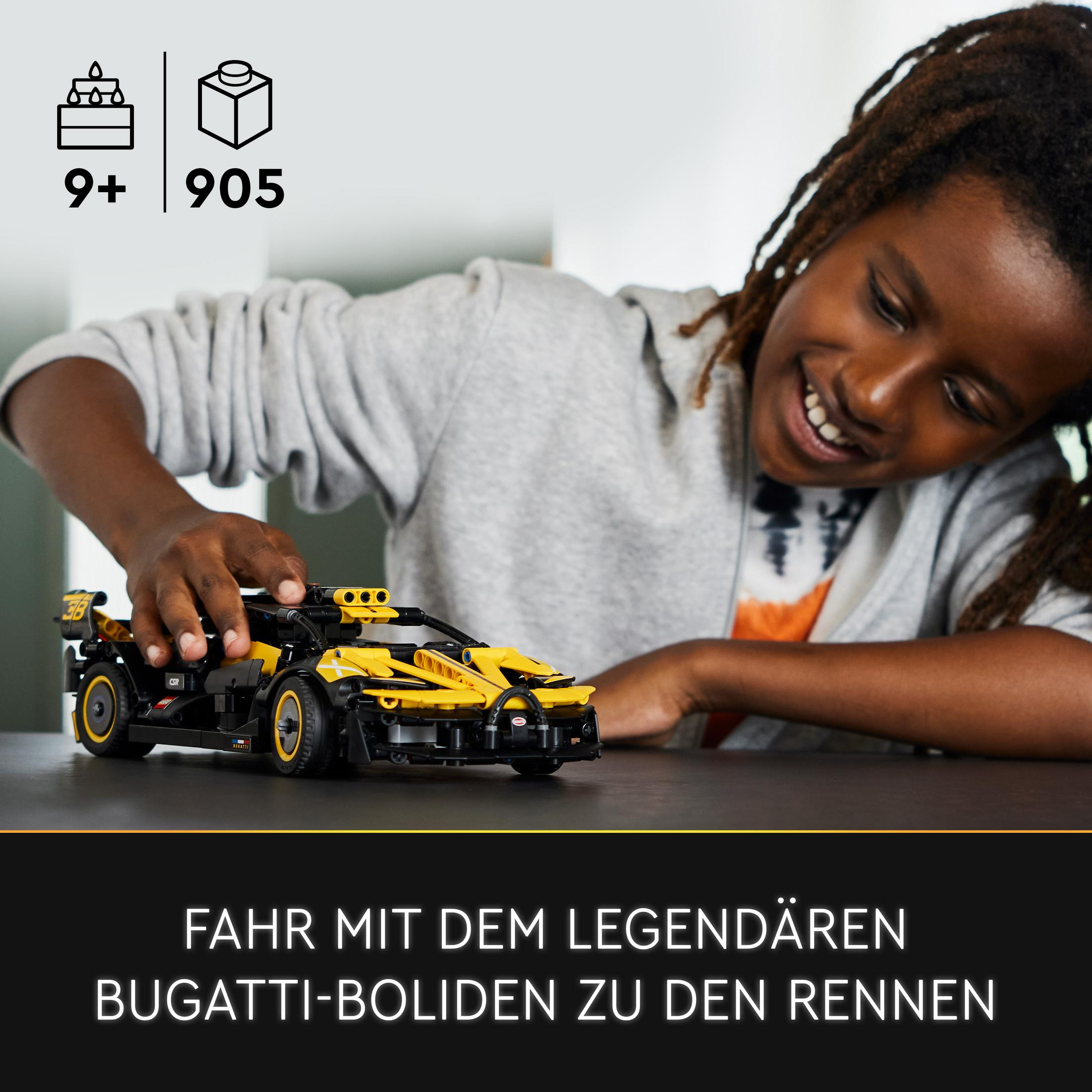 Chłopiec uśmiecha się podczas budowania czarno-żółtego samochodu wyścigowego Lego Bugatti, z tekstem Fahr mit dem legendären Bugatti-Boliden zu den Rennen.