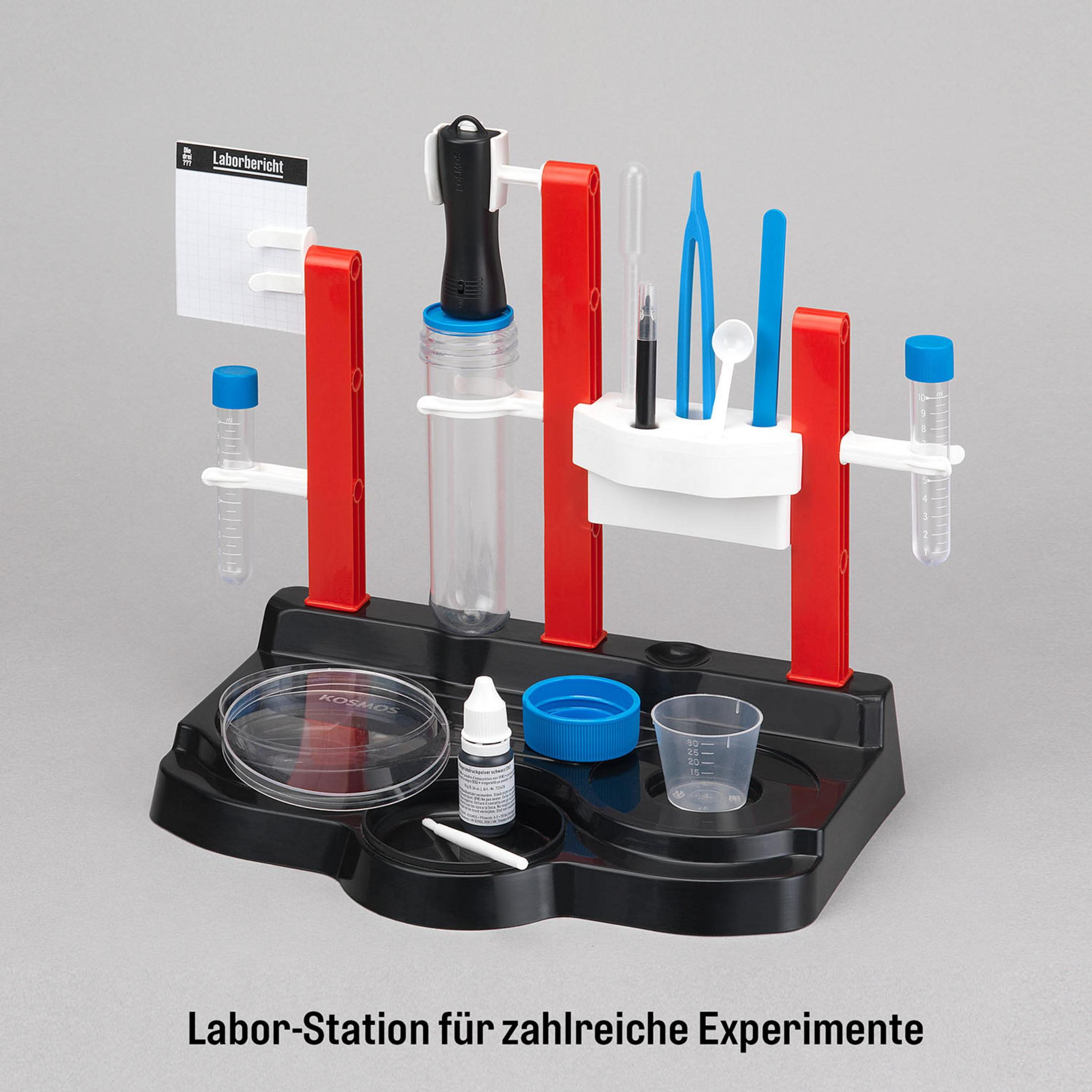 Ein Laborstation mit Bechern, Reagenzgläsern, einer Pipette und einem Notizbuch auf grauem Hintergrund.