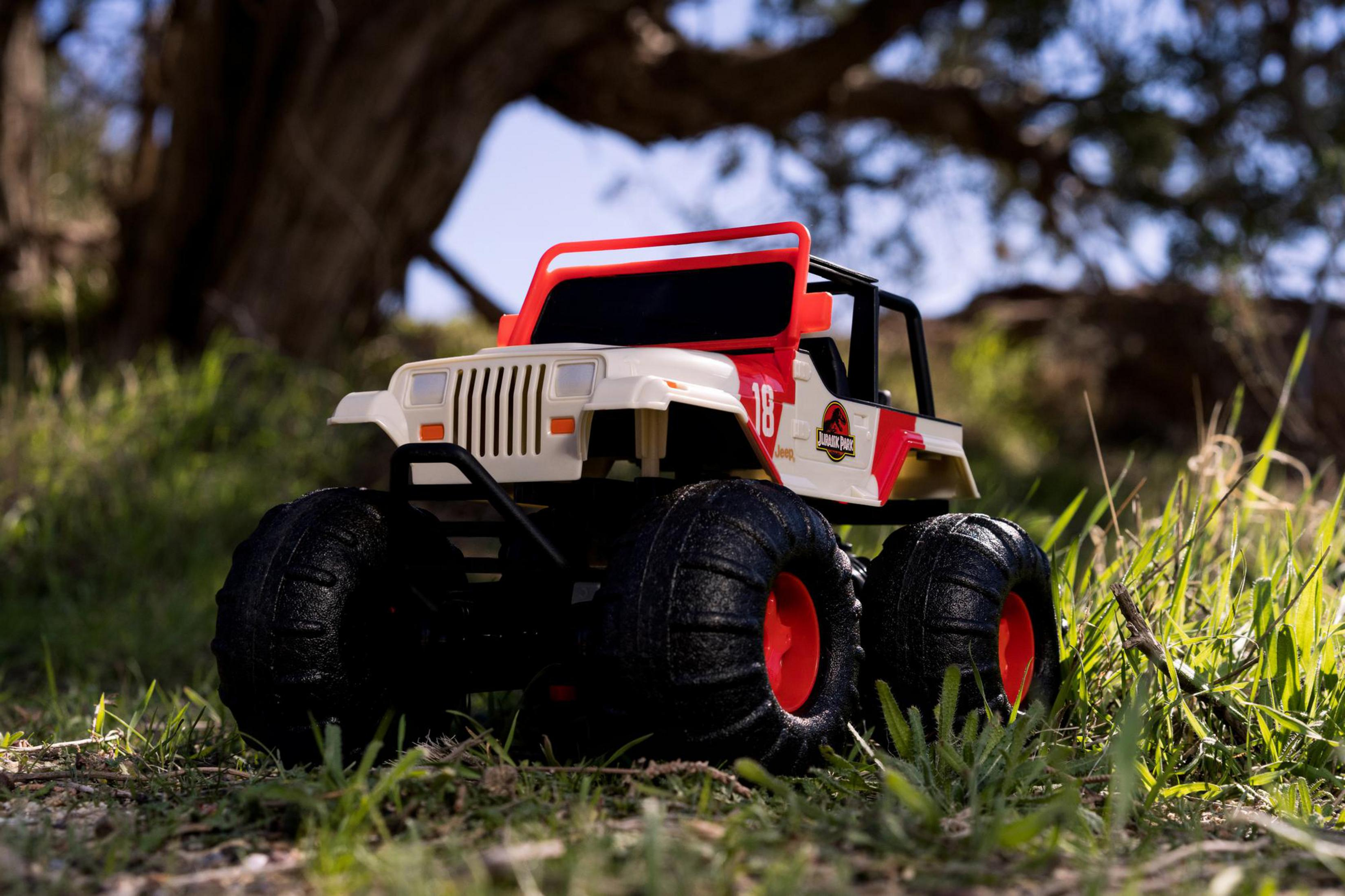 Spielzeug-Jeep auf Gras. Weißer Körper, rote Akzente, schwarze Reifen. Verschwommener grüner Hintergrund.