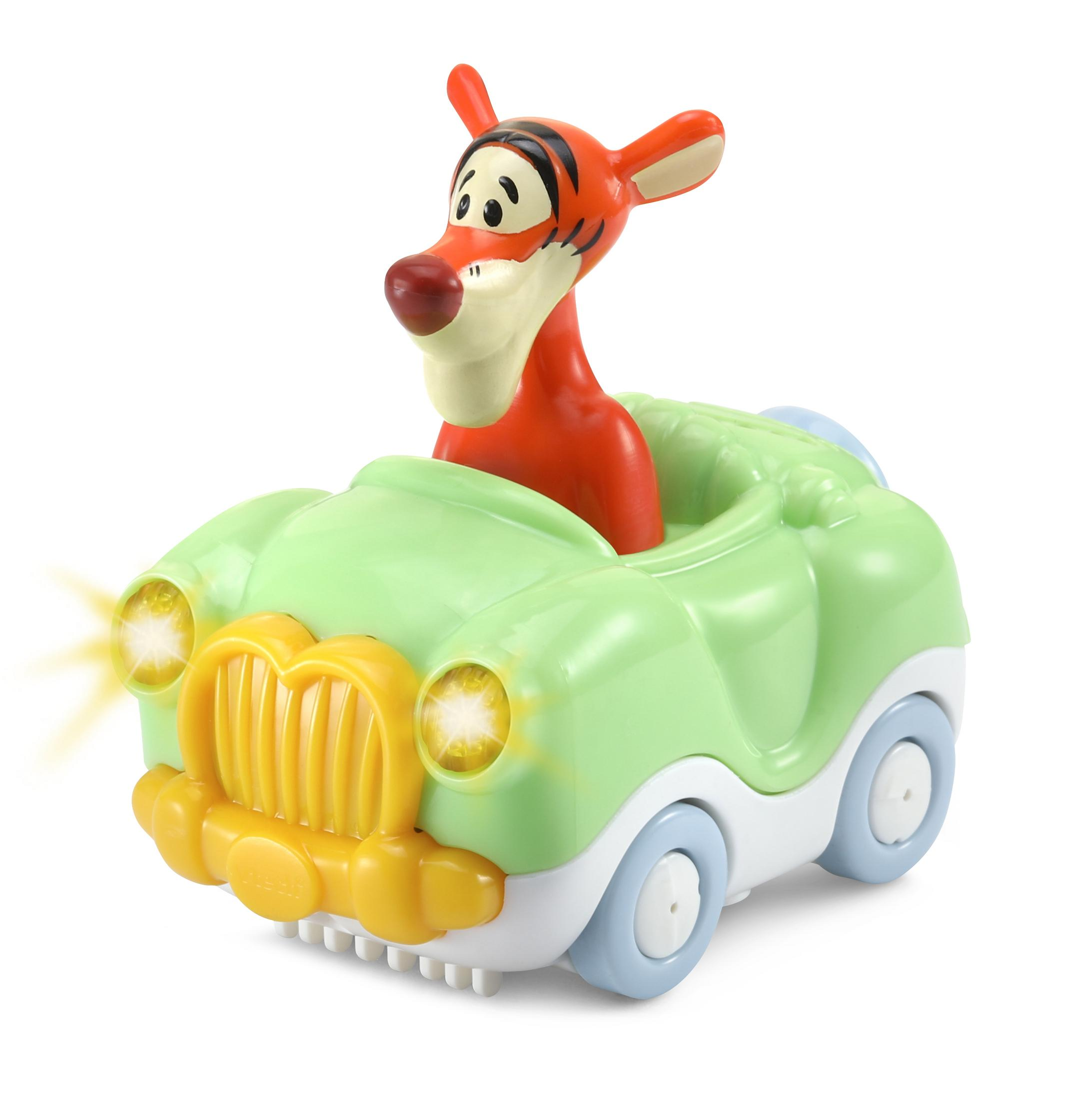 Tigger-Spielzeug in einem grünen Auto. Das Auto hat gelbe Lichter und blaue Räder. Der Tigger ist orange.