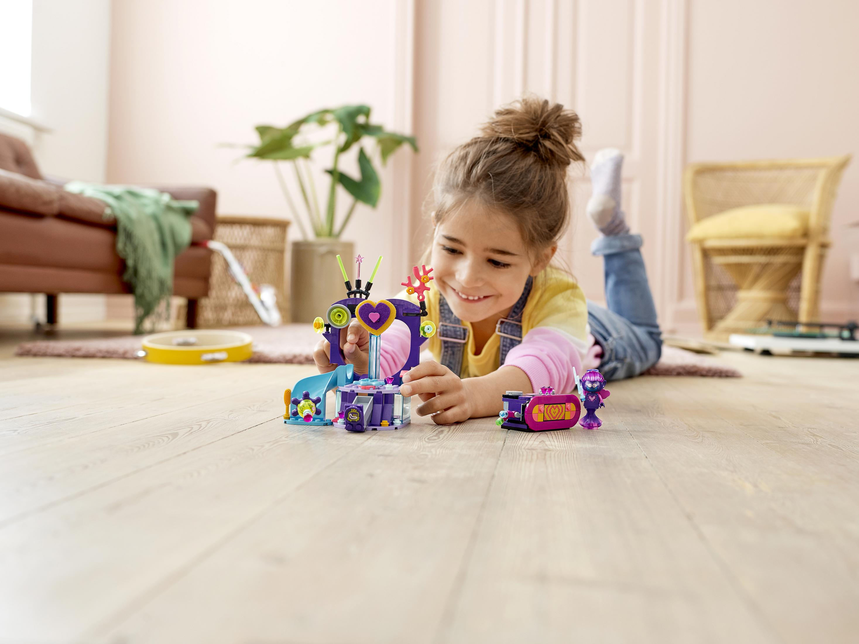 Dziewczynka bawiąca się zabawkami Lego Friends. Fioletowy i różowy zestaw. Leżąca na podłodze.