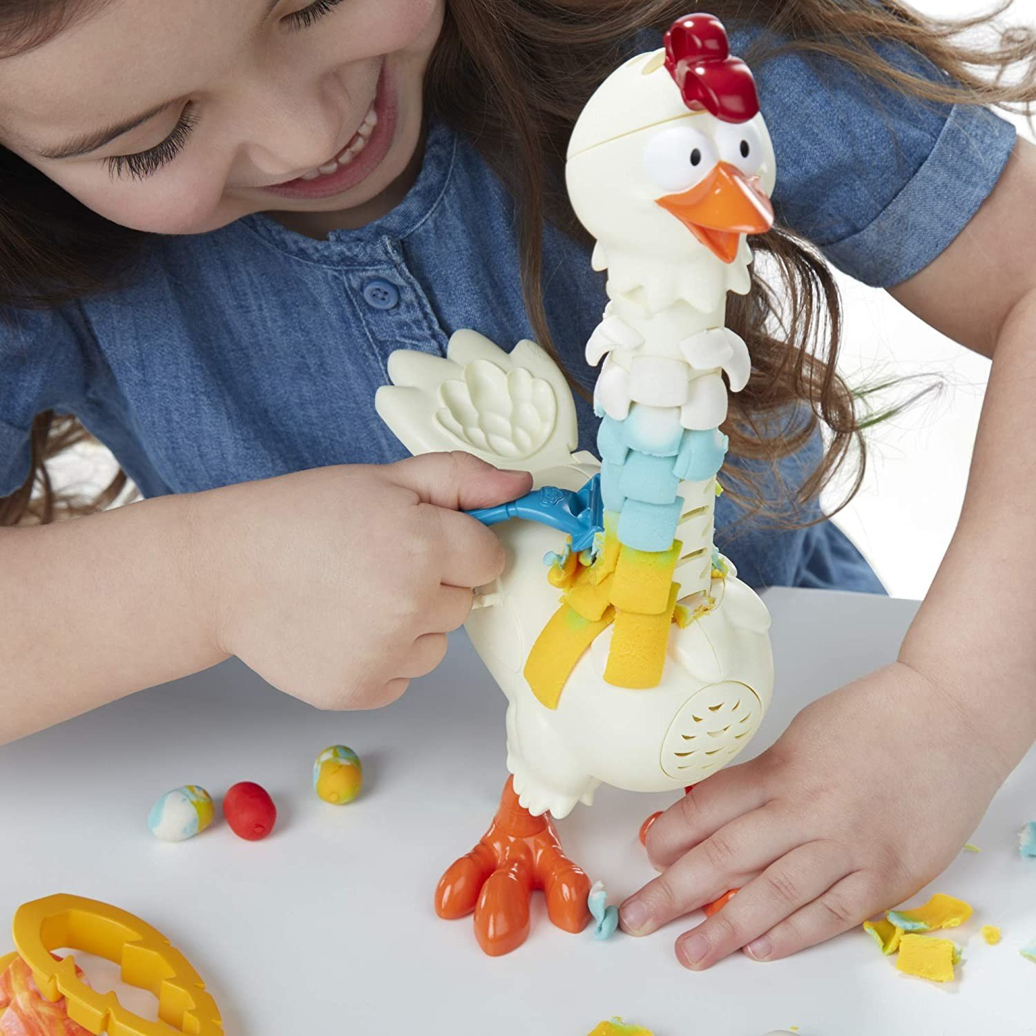 Ein Mädchen spielt mit einem Spielzeug-Huhn. Das Huhn hat einen segmentierten Hals und orange Füße.