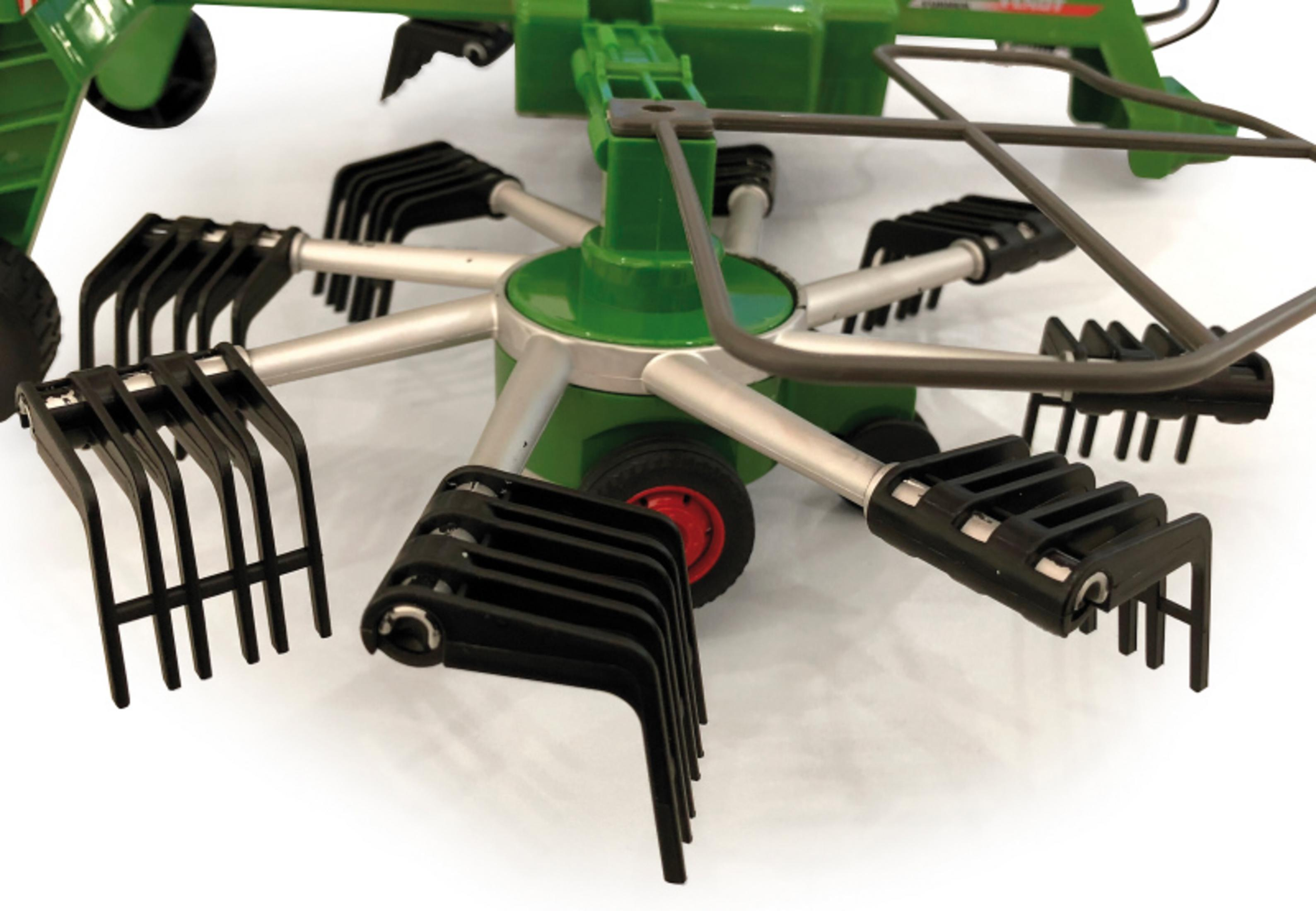 Primer plano de los dientes de rastrillo en una máquina agrícola de juguete verde. También se ven ruedas rojas y la palabra Fendt.